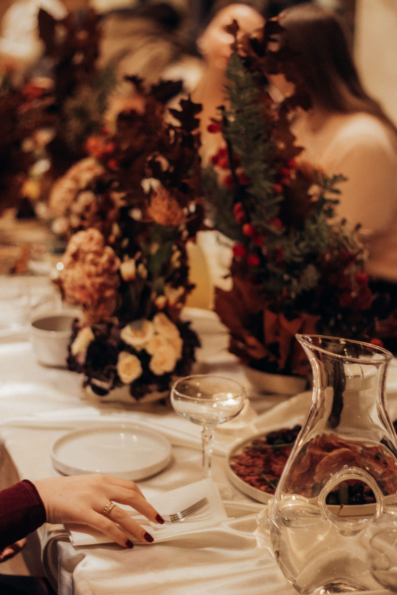 A beautifully decorated holiday dinner table with floral centerpieces and elegant dinnerware.