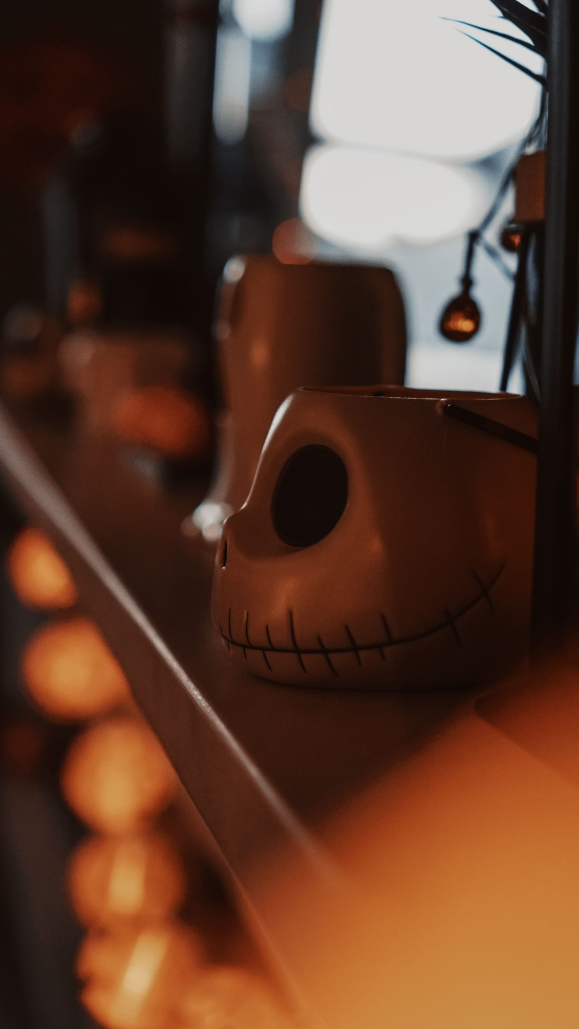 A close-up of a Halloween-themed skull mug on a dimly lit shelf, perfect for festive decor.