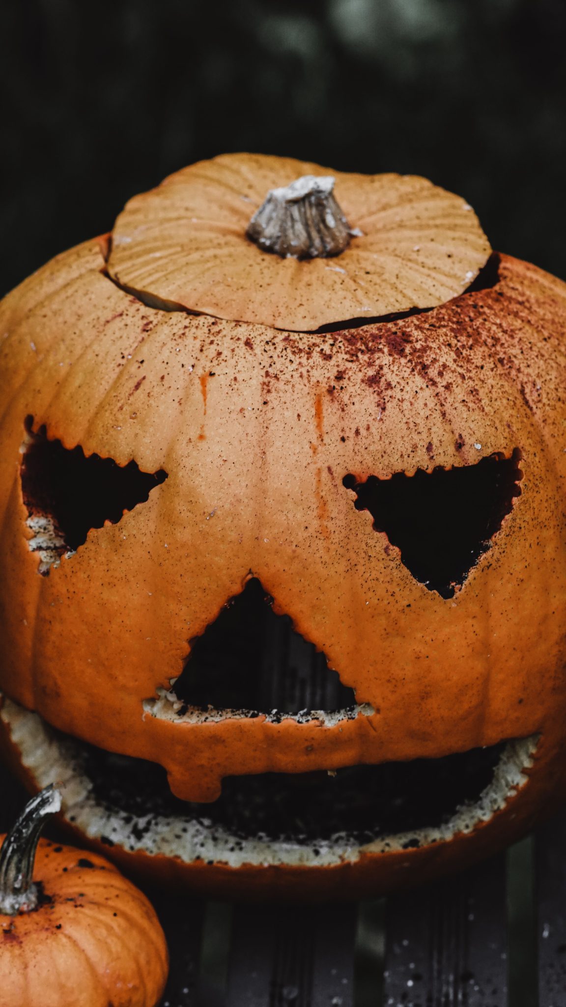 A close-up of a spooky carved jack-o'-lantern with triangular eyes and a grinning mouth, perfect for Halloween.