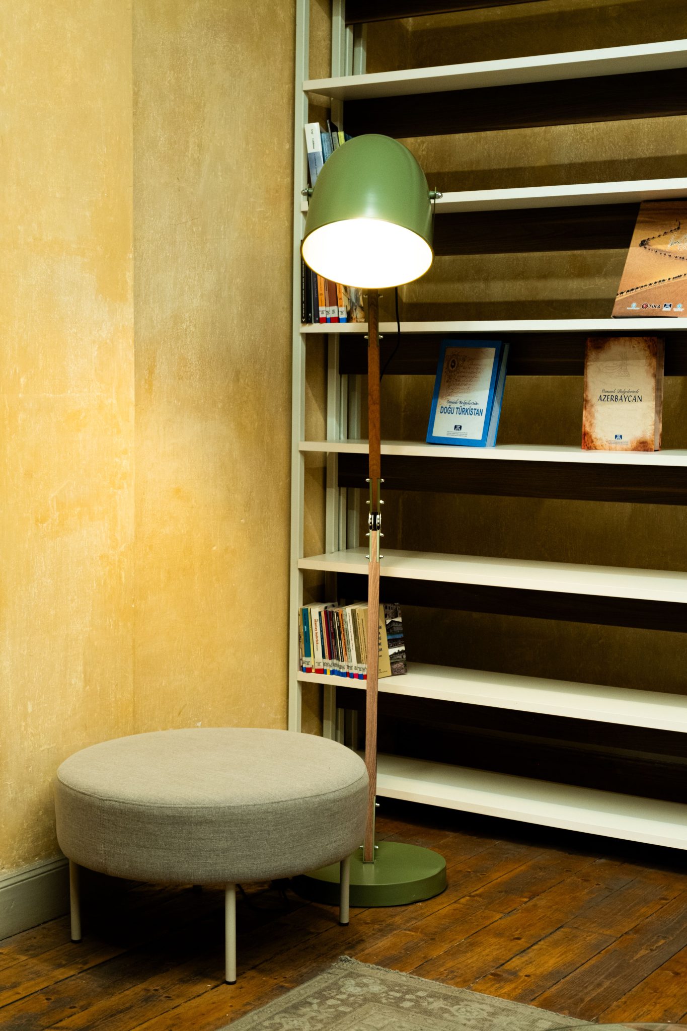 A cozy reading nook featuring a modern lamp and bookshelf with scattered books.