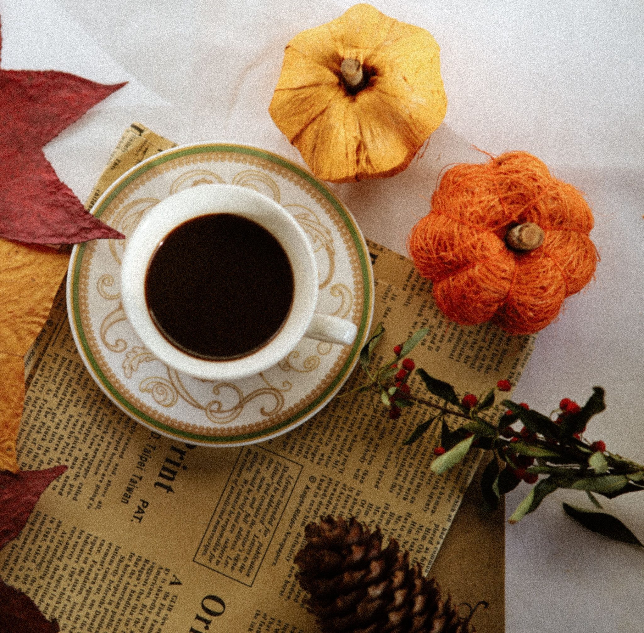 A cup of coffee on autumn leaves and decor, capturing warm seasonal vibes.