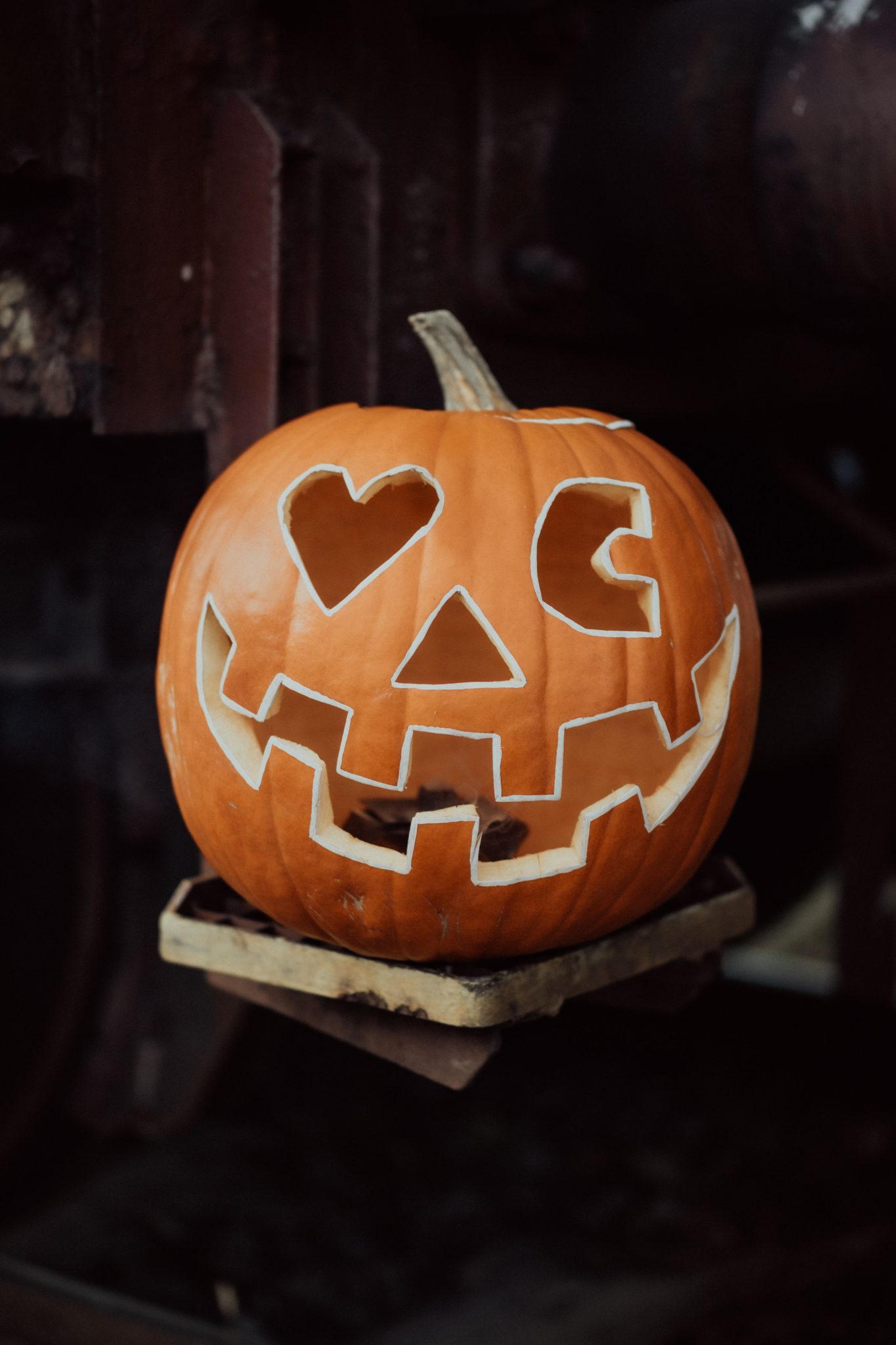 A festive carved pumpkin with heart eyes on a wooden surface, perfect for Halloween.