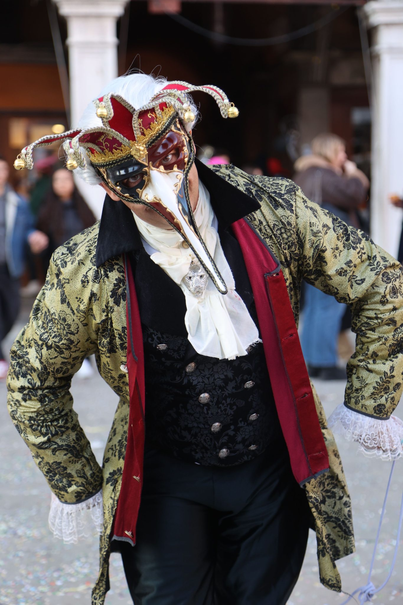 A person in an ornate masquerade costume at a Venice festival, featuring intricate mask and attire.