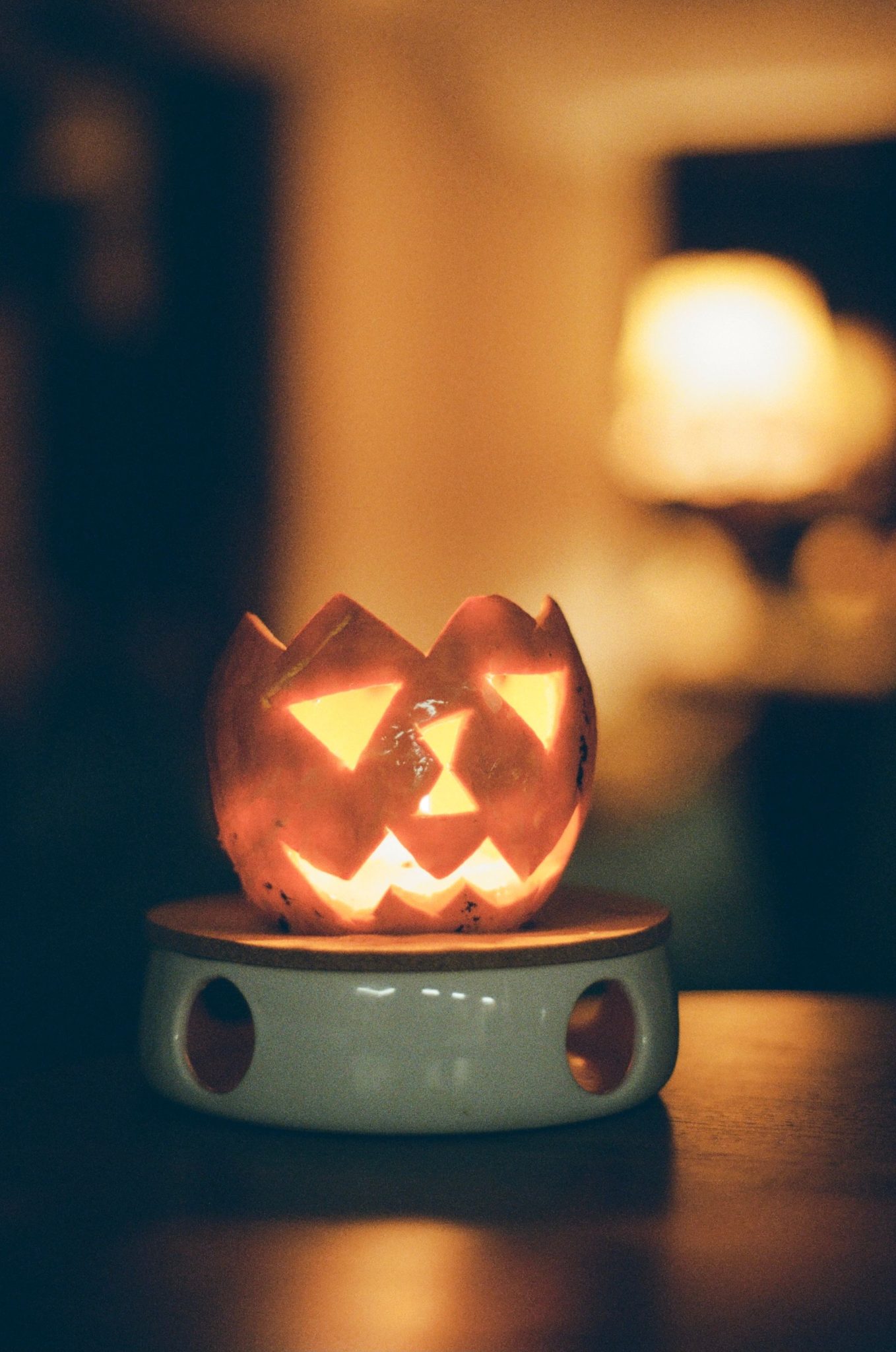 A pumpkin-shaped ceramic candle holder glowing warmly, perfect for Halloween decor.