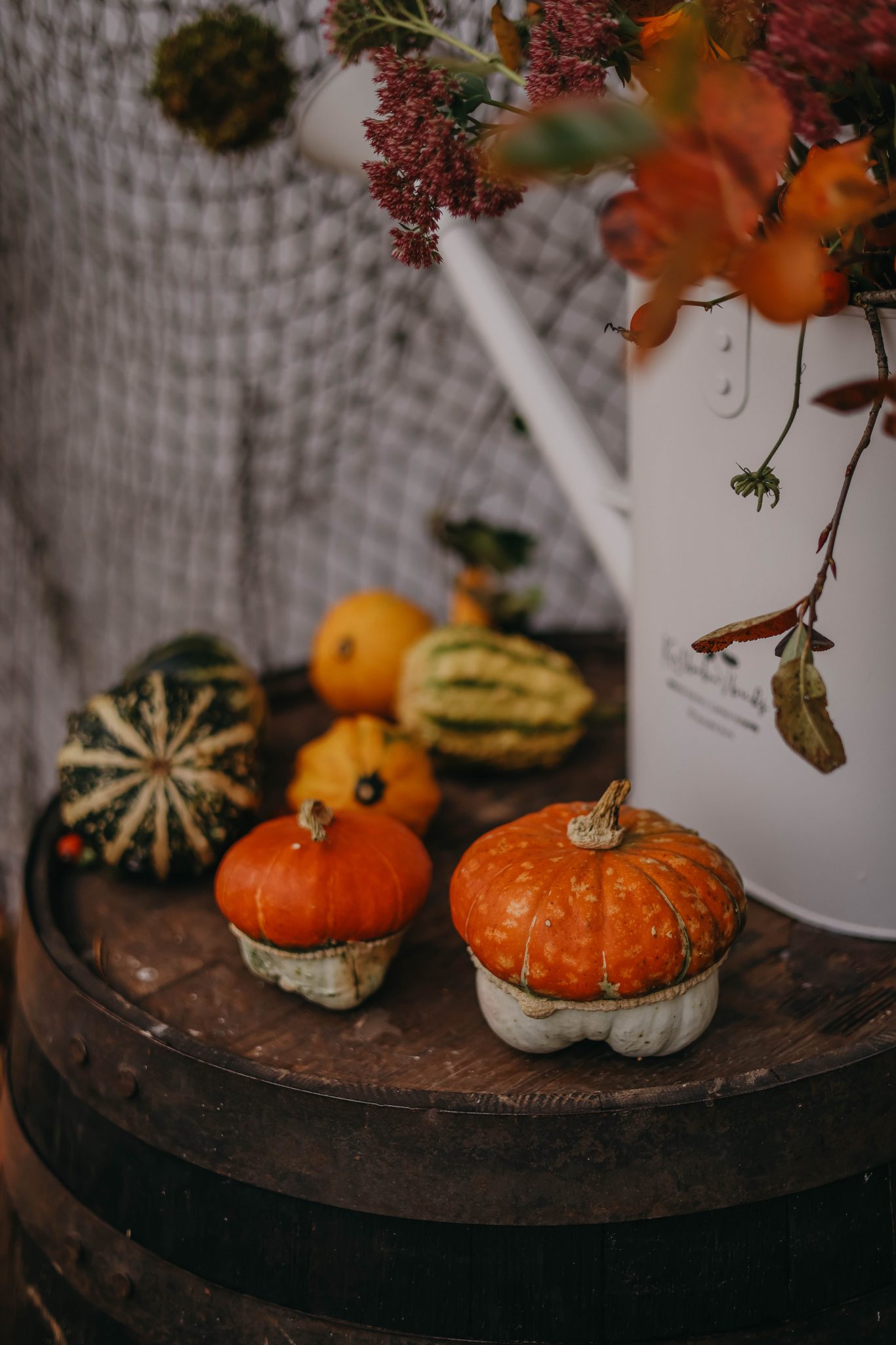 A rustic autumn display featuring pumpkins and gourds on a wooden barrel, perfect for fall decor.