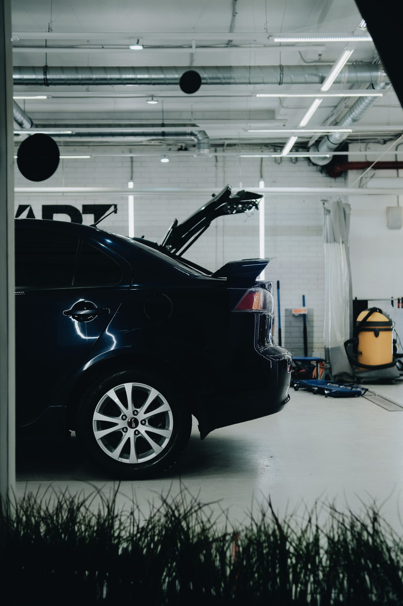 A sleek sedan undergoing maintenance in a modern auto repair workshop indoors.
