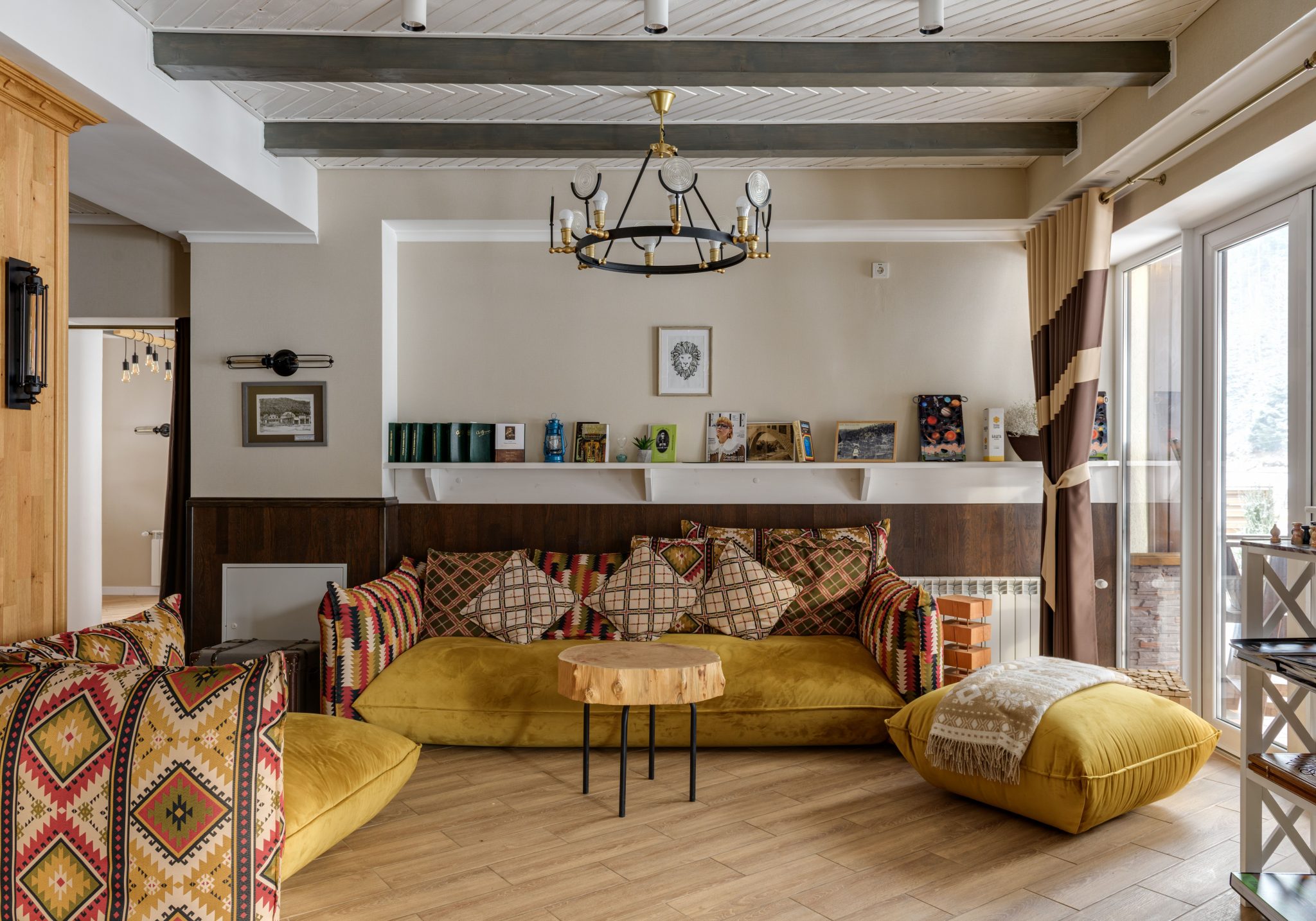 A stylish living room featuring a yellow sofa, chandelier, and eclectic decor with ample natural light.