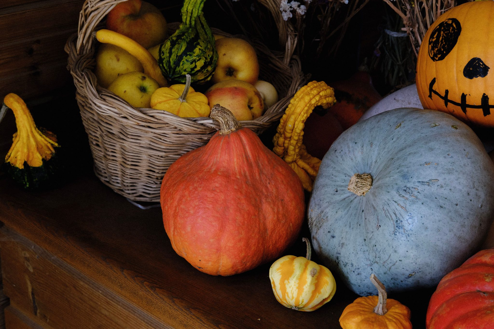 A vibrant assortment of autumn harvest fruits and gourds displayed with a basket of apples.