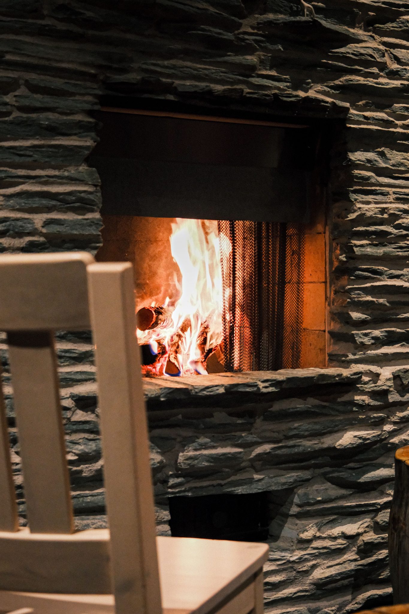 A warm and inviting stone fireplace with a crackling firewood flame inside, offering a cozy atmosphere.