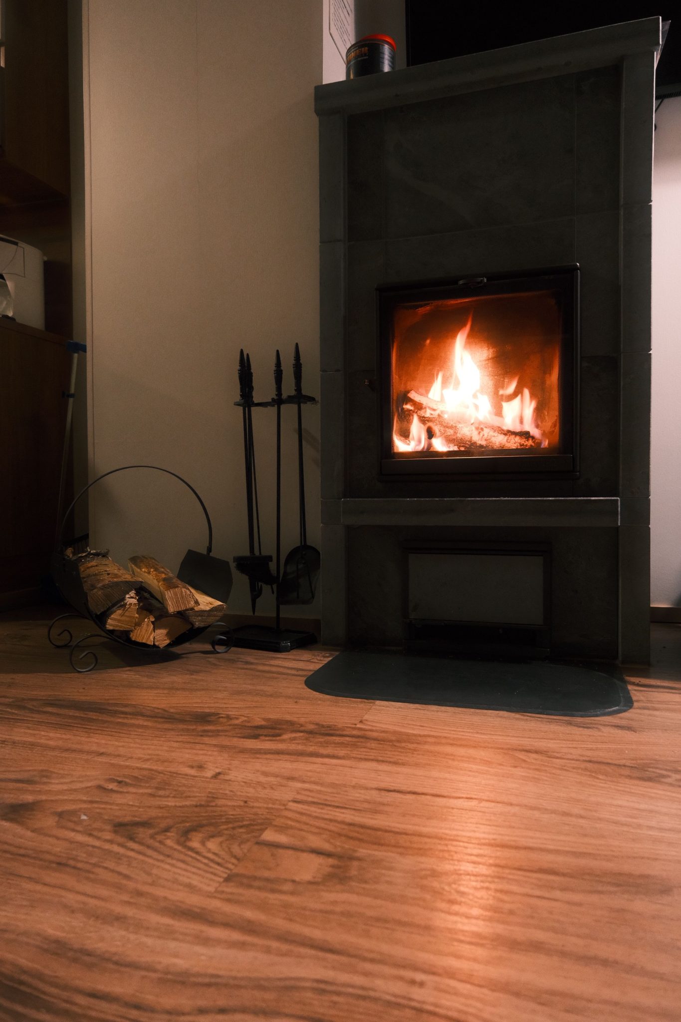A warm indoor fireplace with logs and tools, perfect for a cozy ambiance.