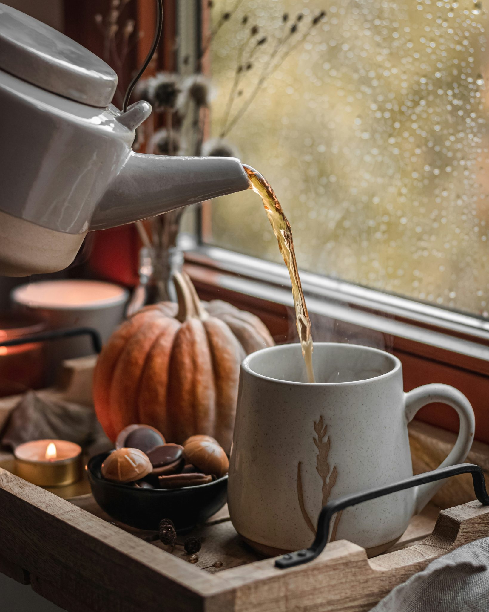 Autumn tea on window with candle and pumpkin 
