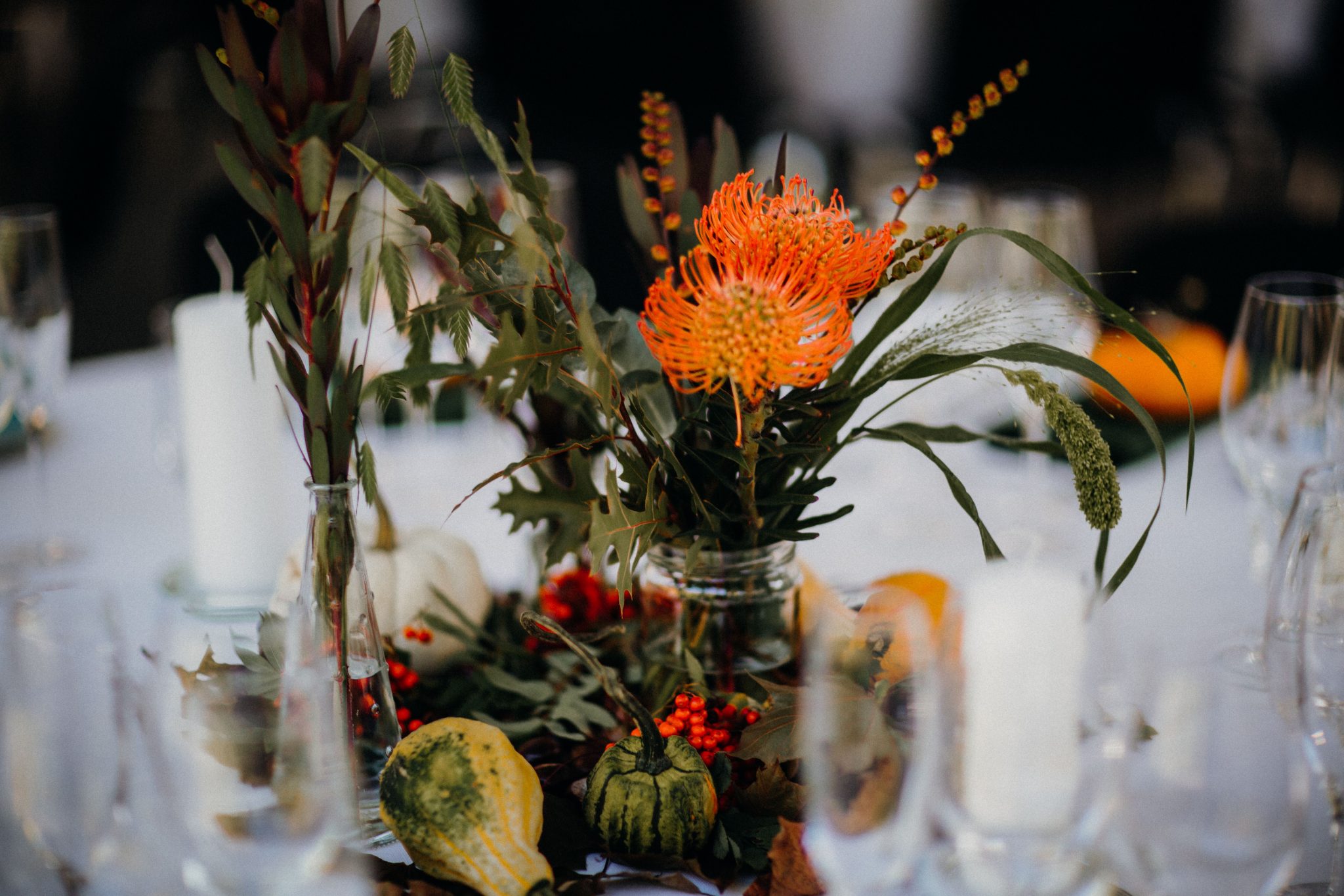 Autumn-themed table setting with vibrant floral centerpiece and pumpkins.