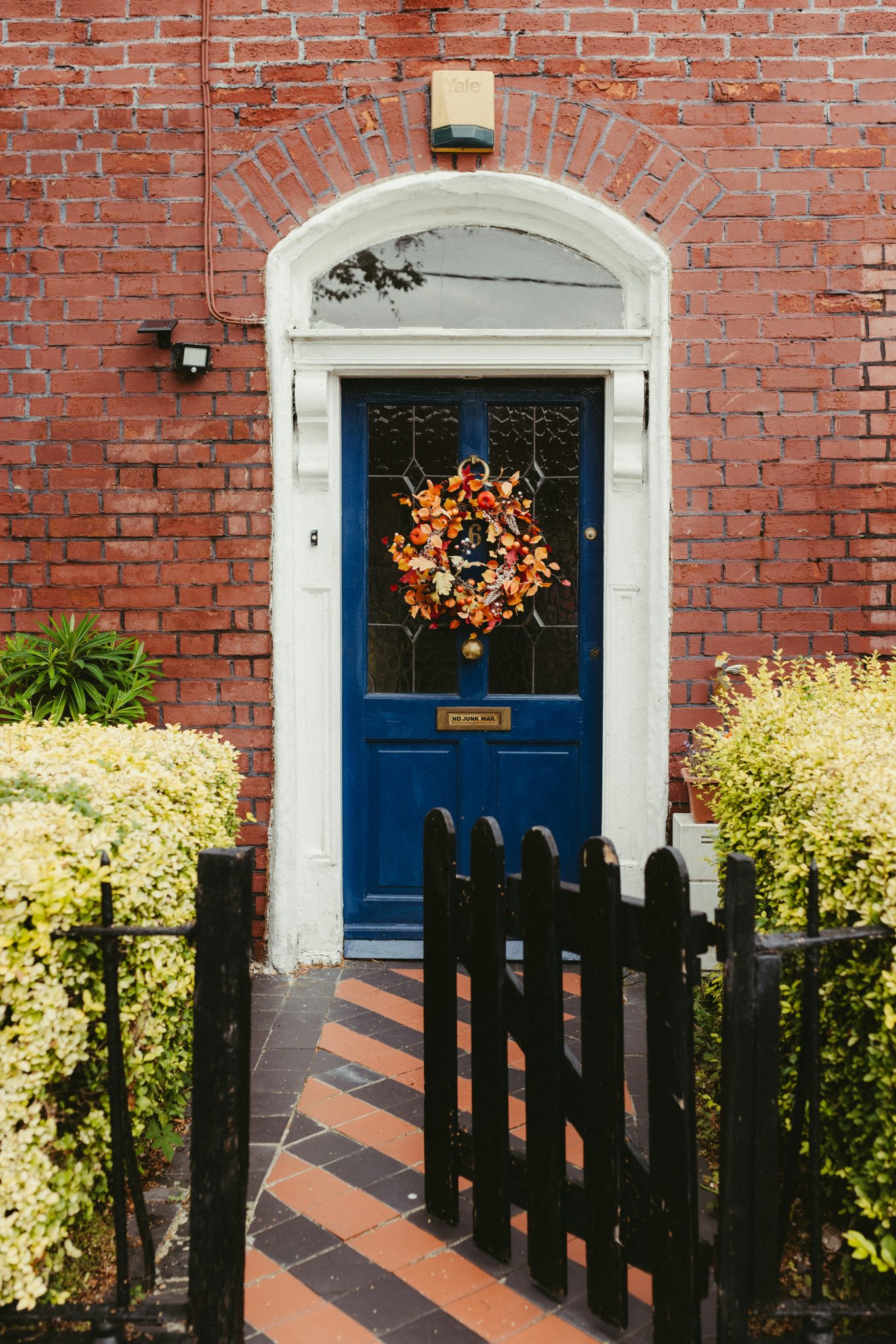 Blue front door with autumnal wreath on a brick house.