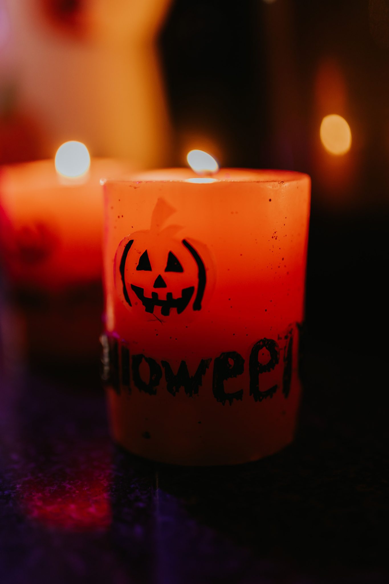 Bright orange Halloween candle with a jack-o'-lantern design, perfect for spooky decor.
