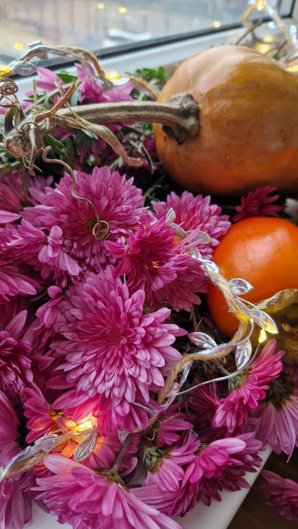 Captivating autumn display featuring chrysanthemums, gourds, and fairy lights.