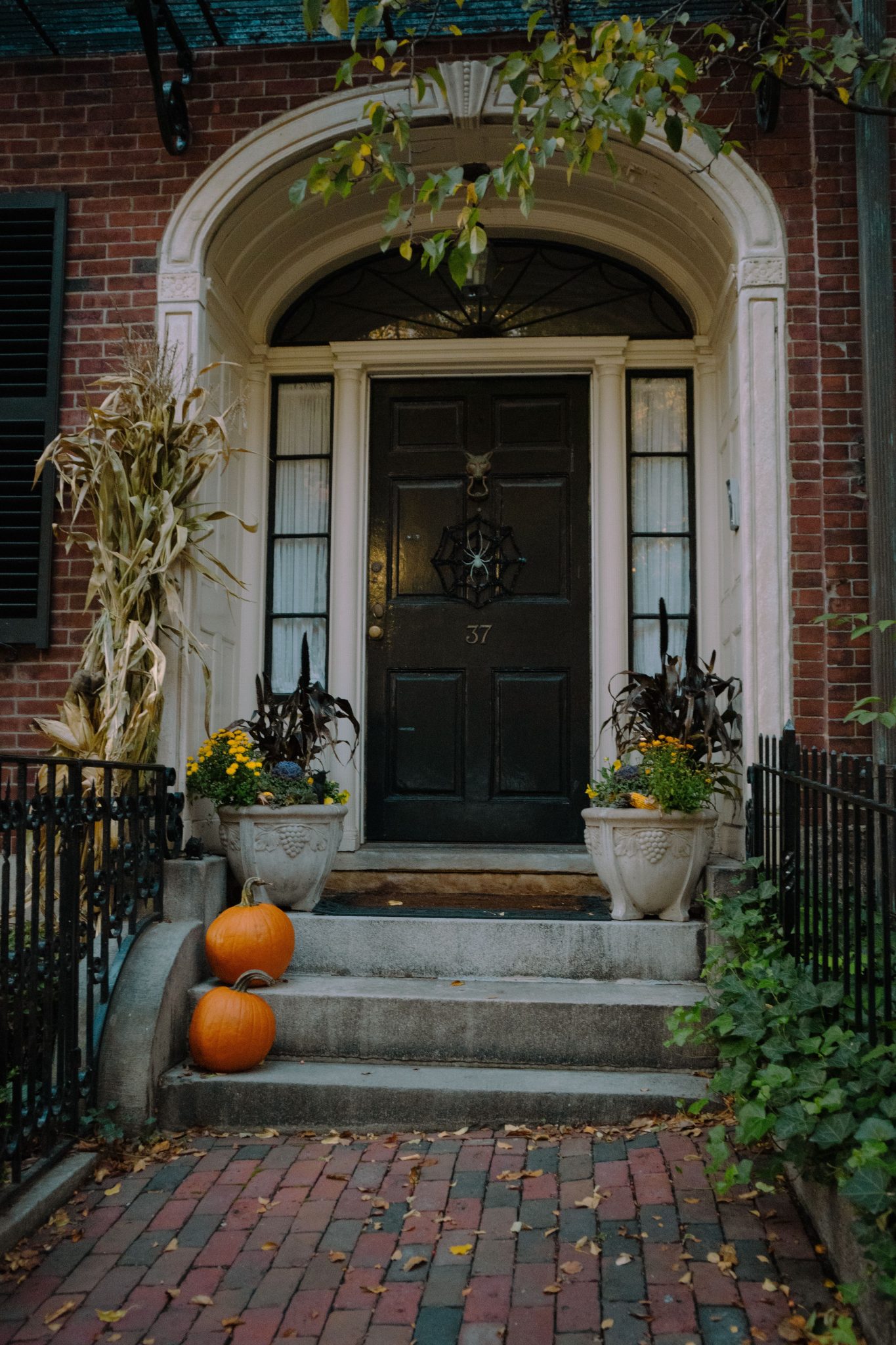 Charming brick home with pumpkins and autumn decor on the front steps.