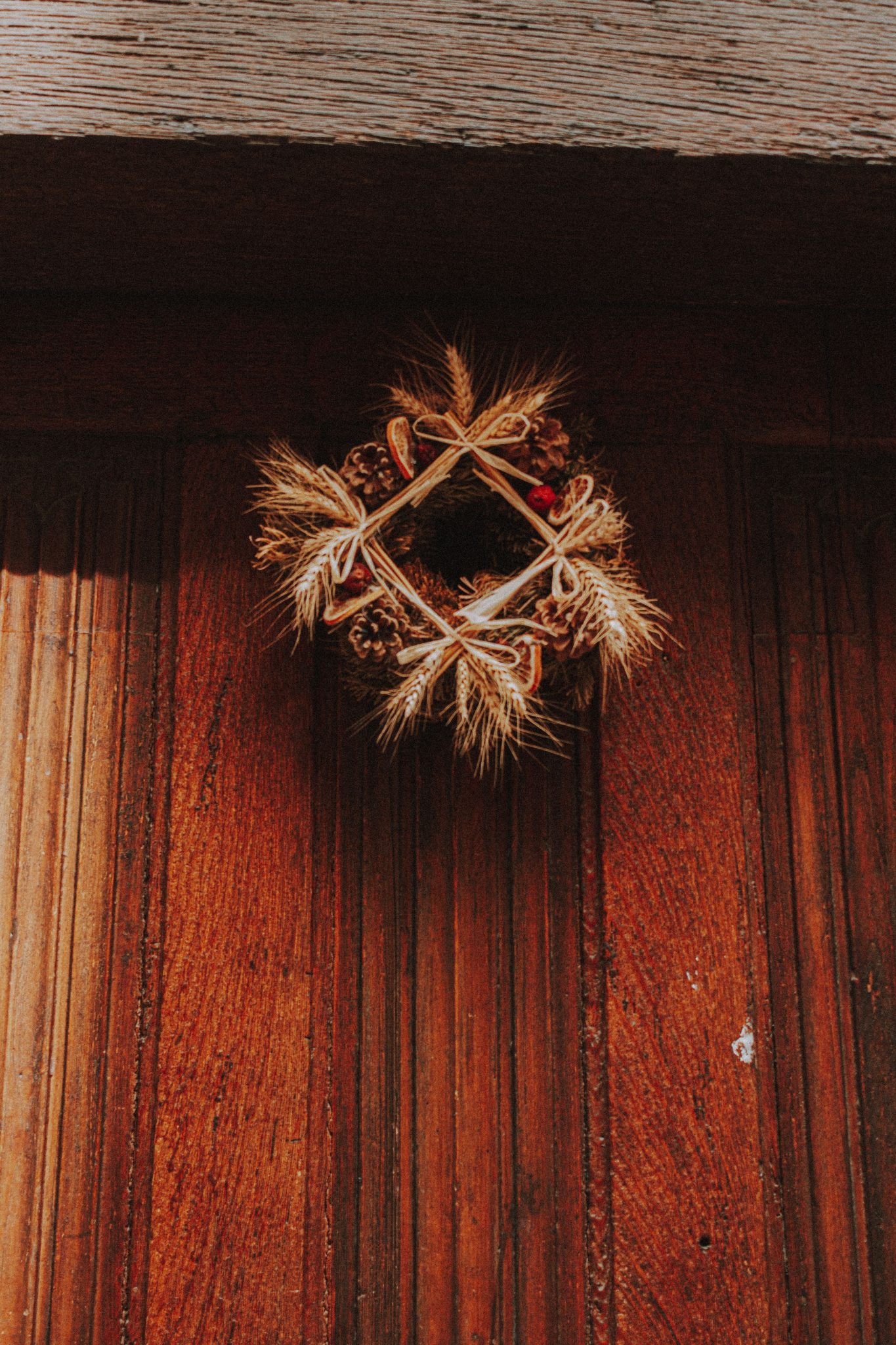 Close-up of a rustic wooden door with a natural decorative wreath, perfect for autumn themes.