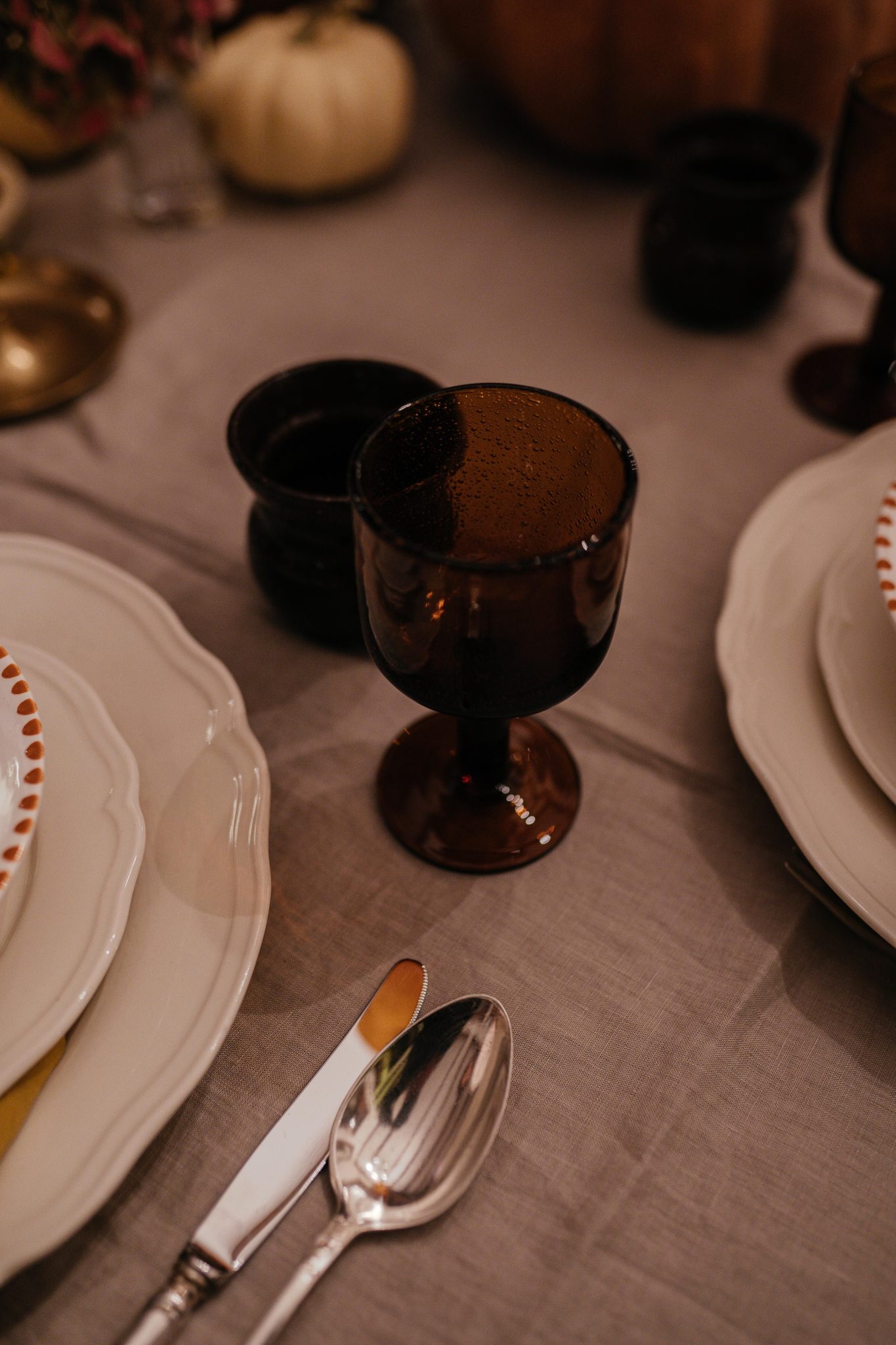 Close-up of an autumn dining table setup featuring amber glasses and elegant tableware.