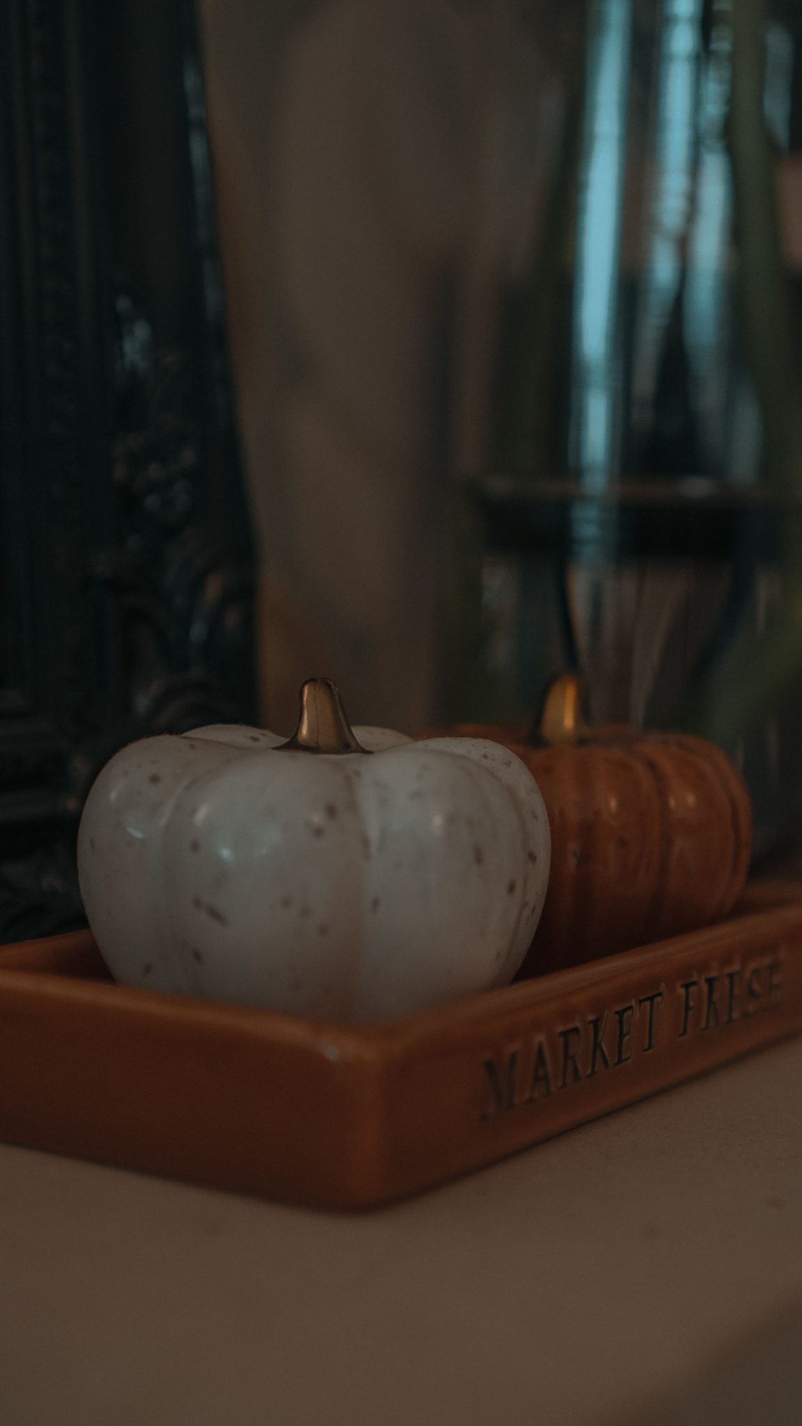 Close-up of ceramic pumpkins placed on a decorative tray indoors, evoking autumn vibes.