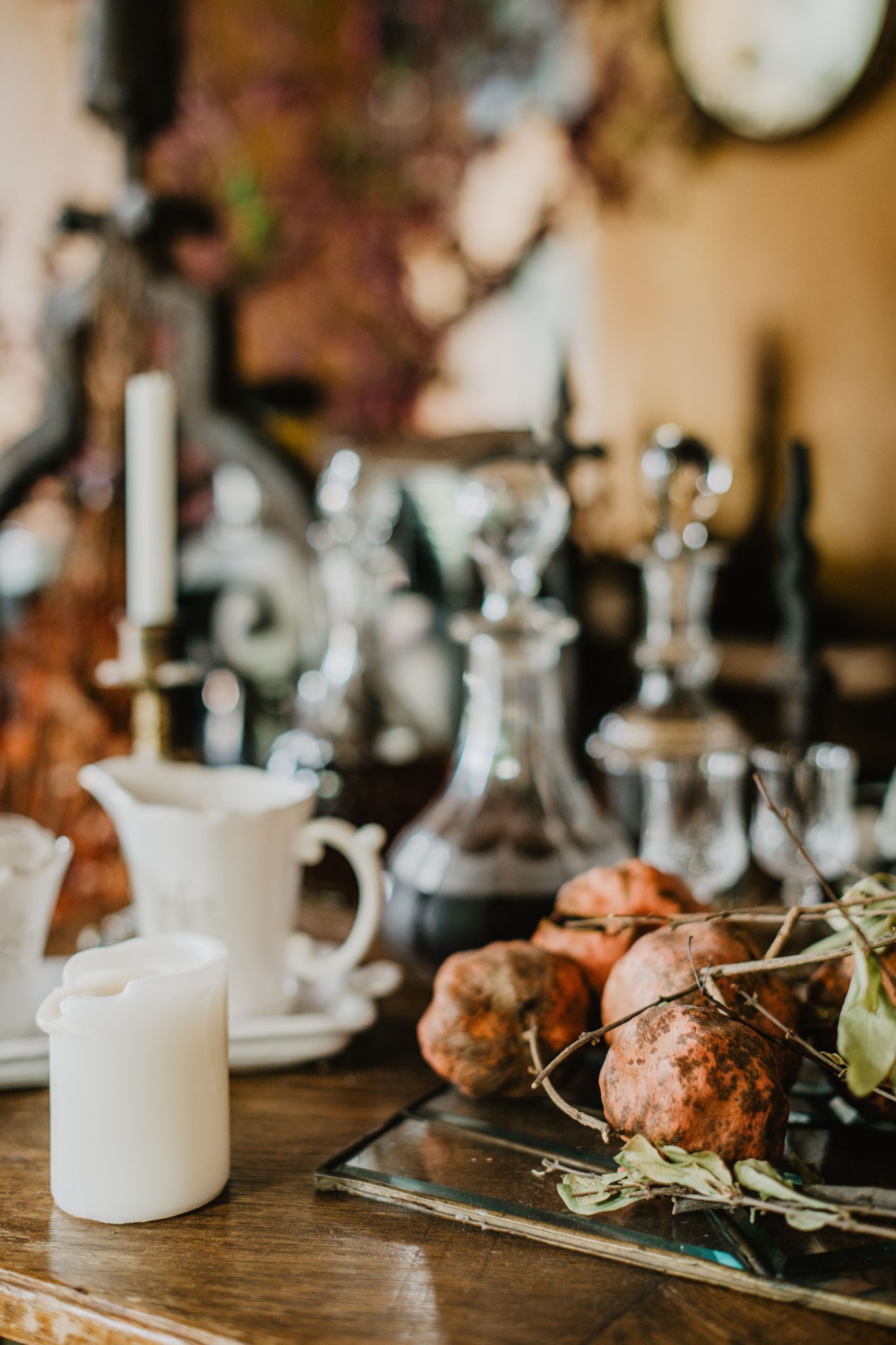 Cozy fall-themed table arrangement featuring candles, glassware, and organic elements.