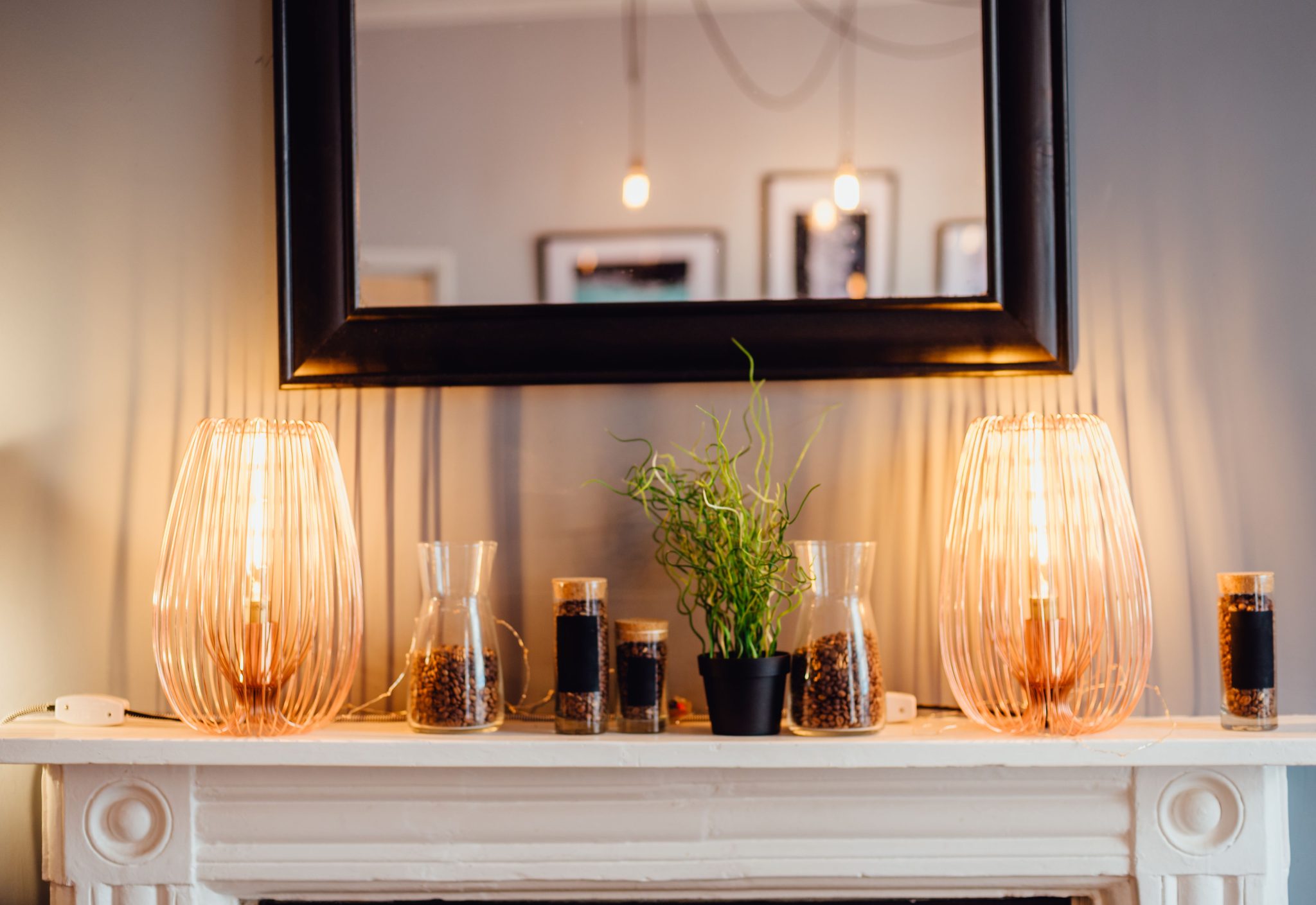 Cozy interior scene with warm light lamps and natural decor on a fireplace mantle.