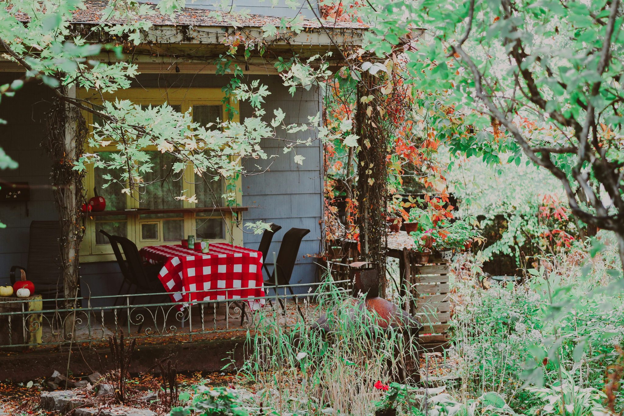 Cozy porch with a checkered tablecloth and chairs.