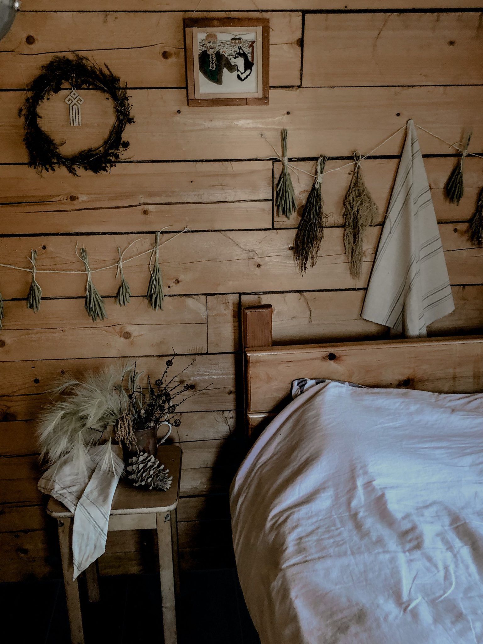 Cozy rustic bedroom featuring wooden walls, natural decorations, and earthy tones.