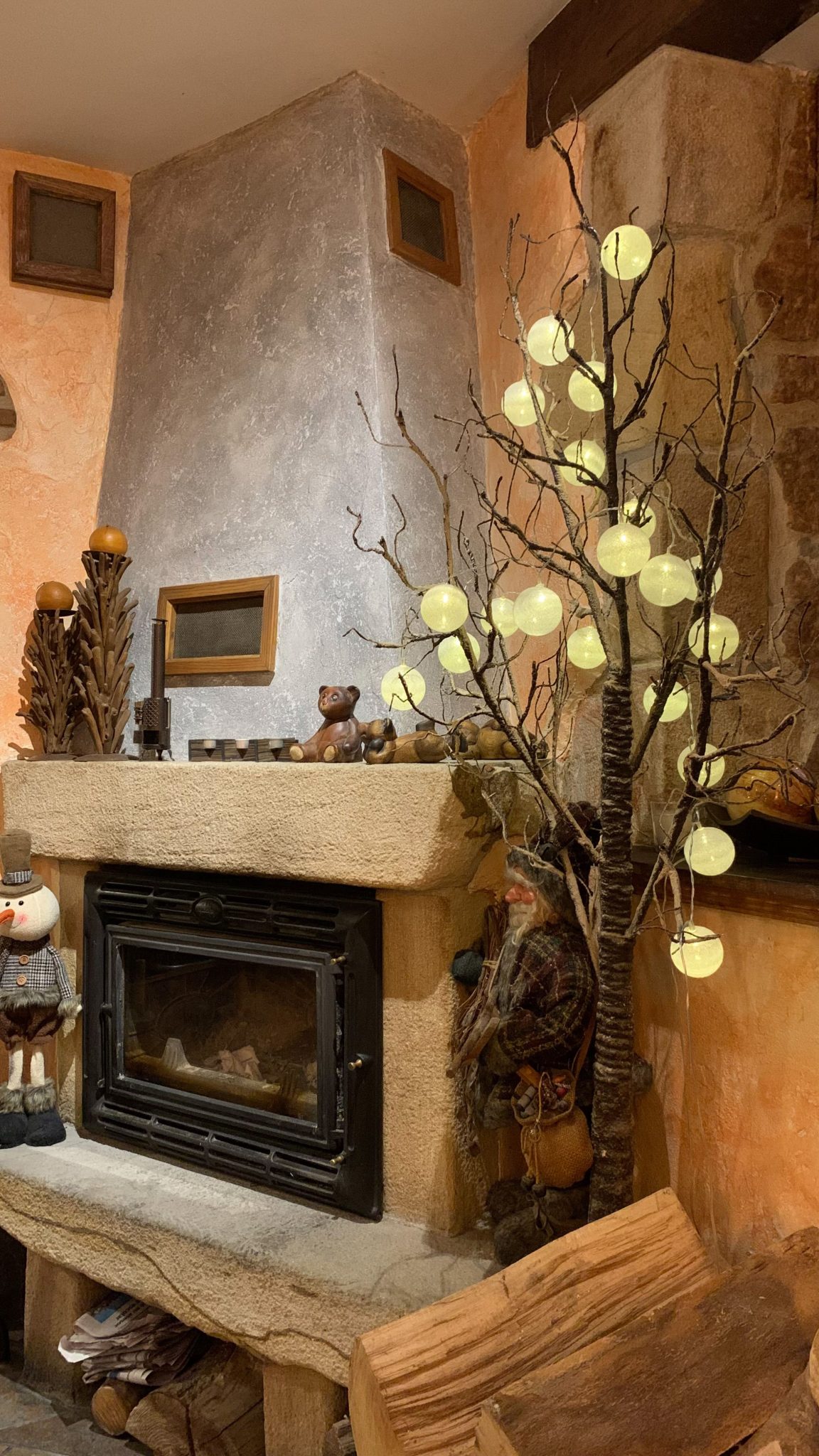 Cozy rustic fireplace decorated for winter with glowing lights and holiday ornaments.