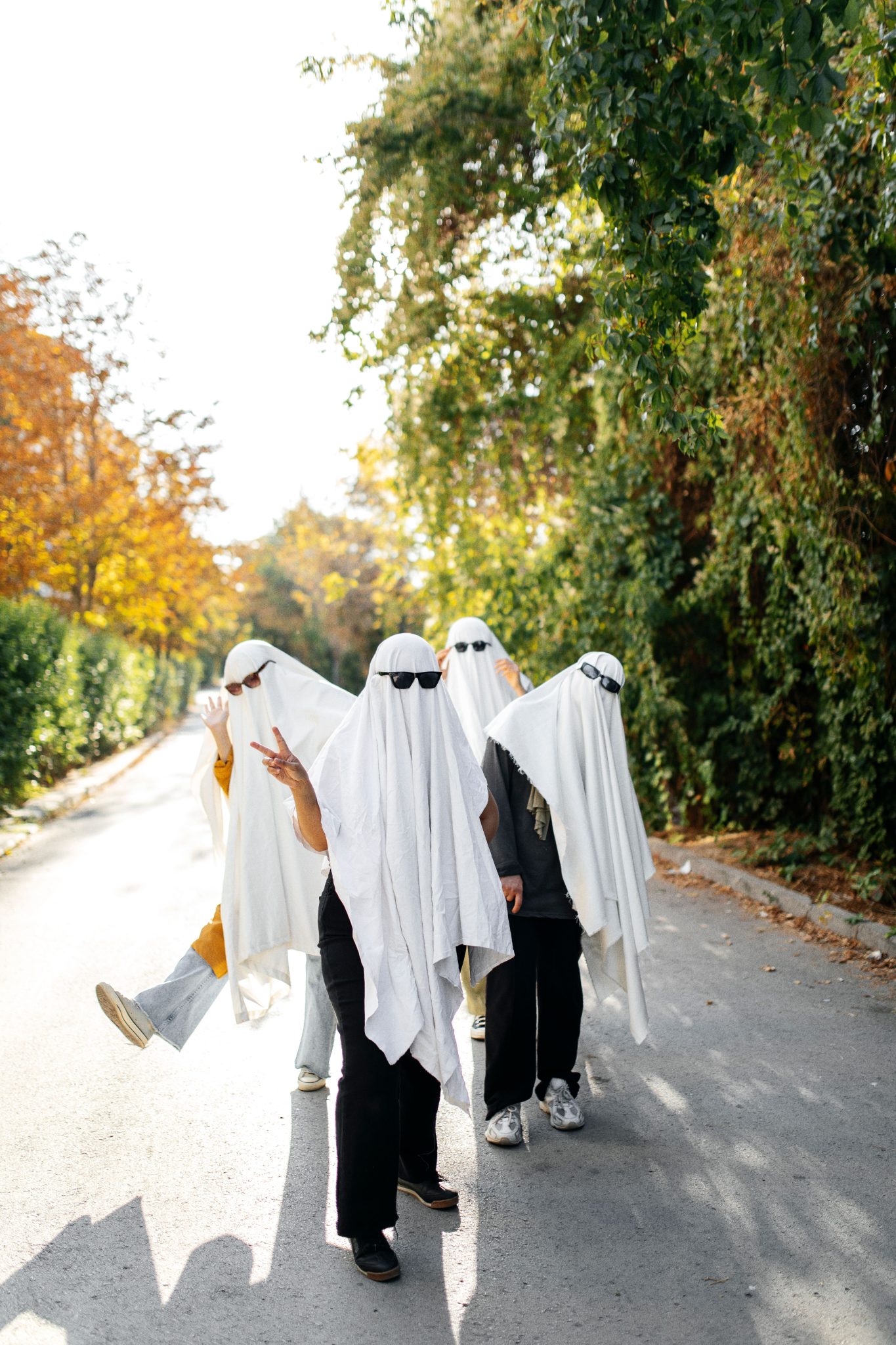 Creative Halloween street scene with group dressed as ghosts featuring white sheets and sunglasses.