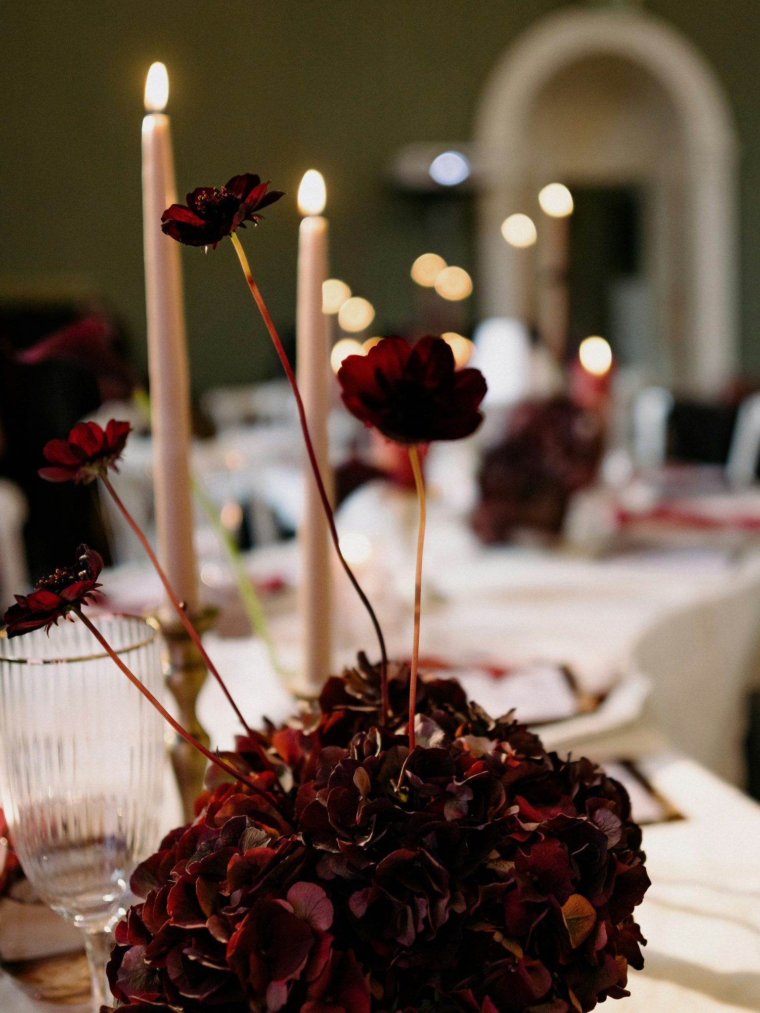 Dark red flowers and tall candles on a table