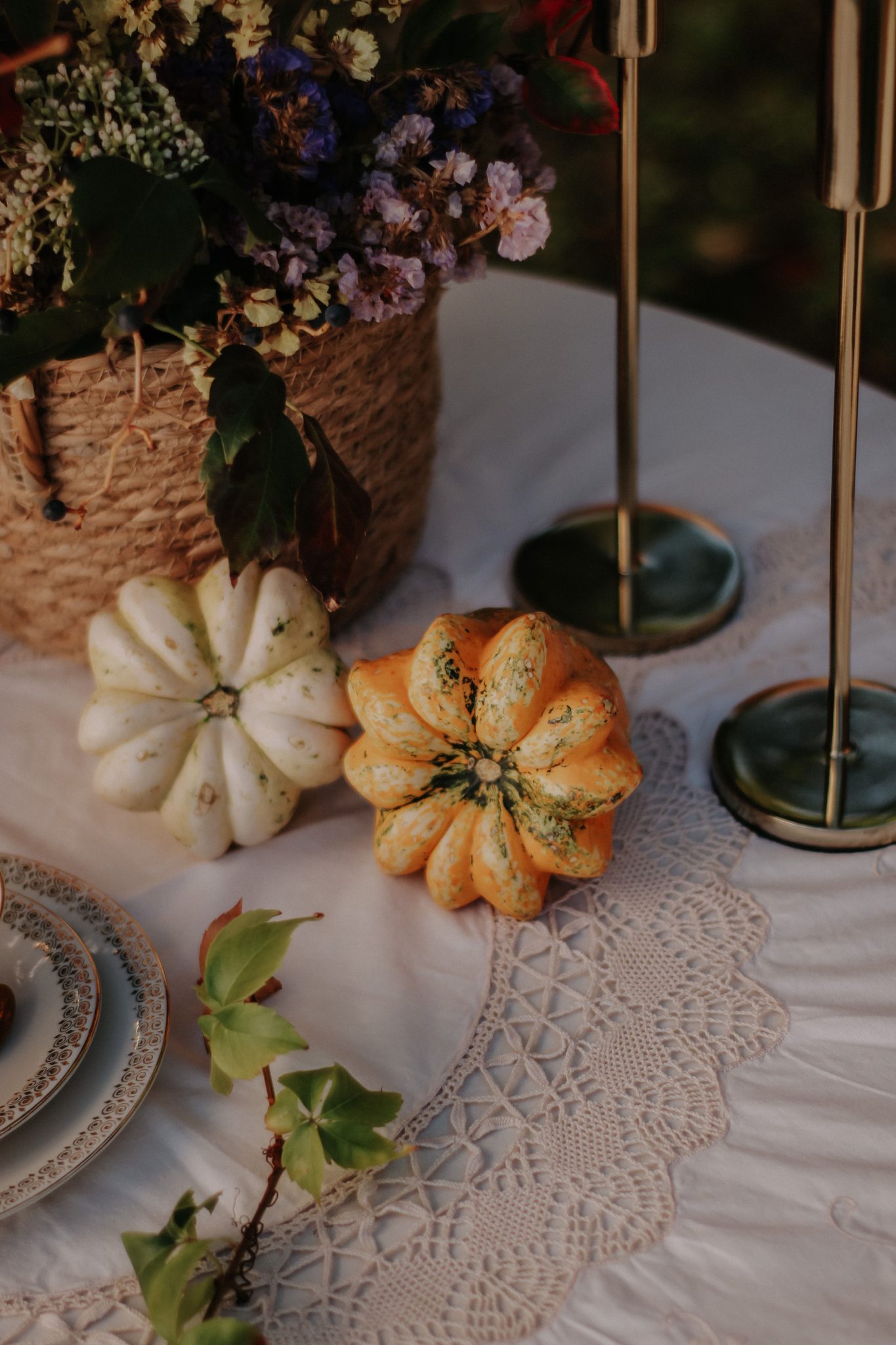 Elegant autumn table setting featuring decorative gourds and flowers on lace cloth.