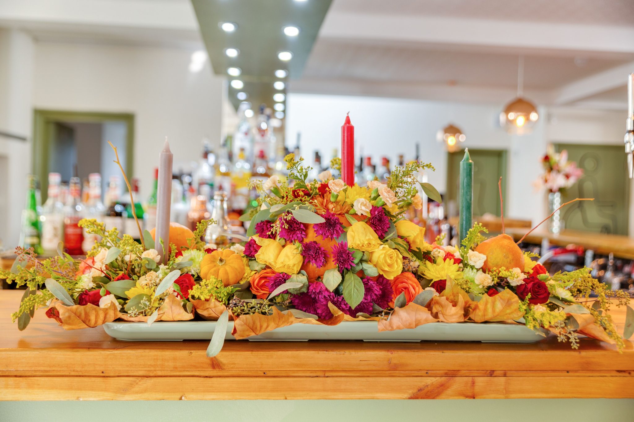 Elegant flower arrangement with vibrant autumn colors and candles, perfect for festive celebrations.