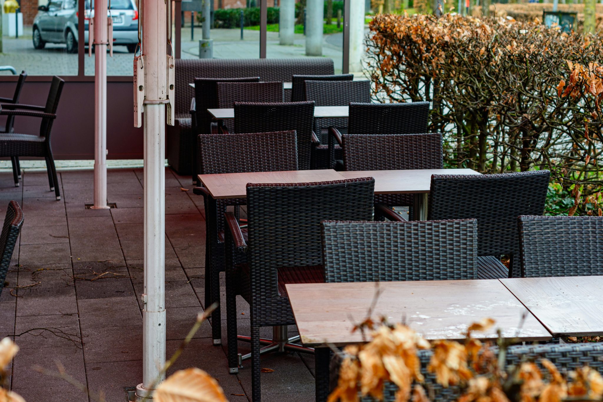 Empty outdoor cafe tables and chairs with dry leaves