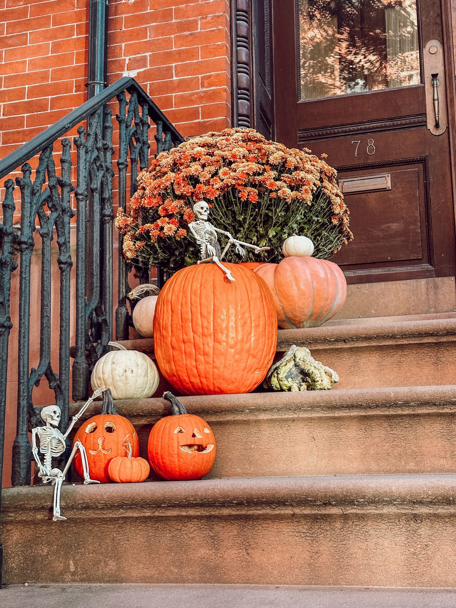 Festive fall decorations of pumpkins and skeletons on brownstone steps in Brooklyn