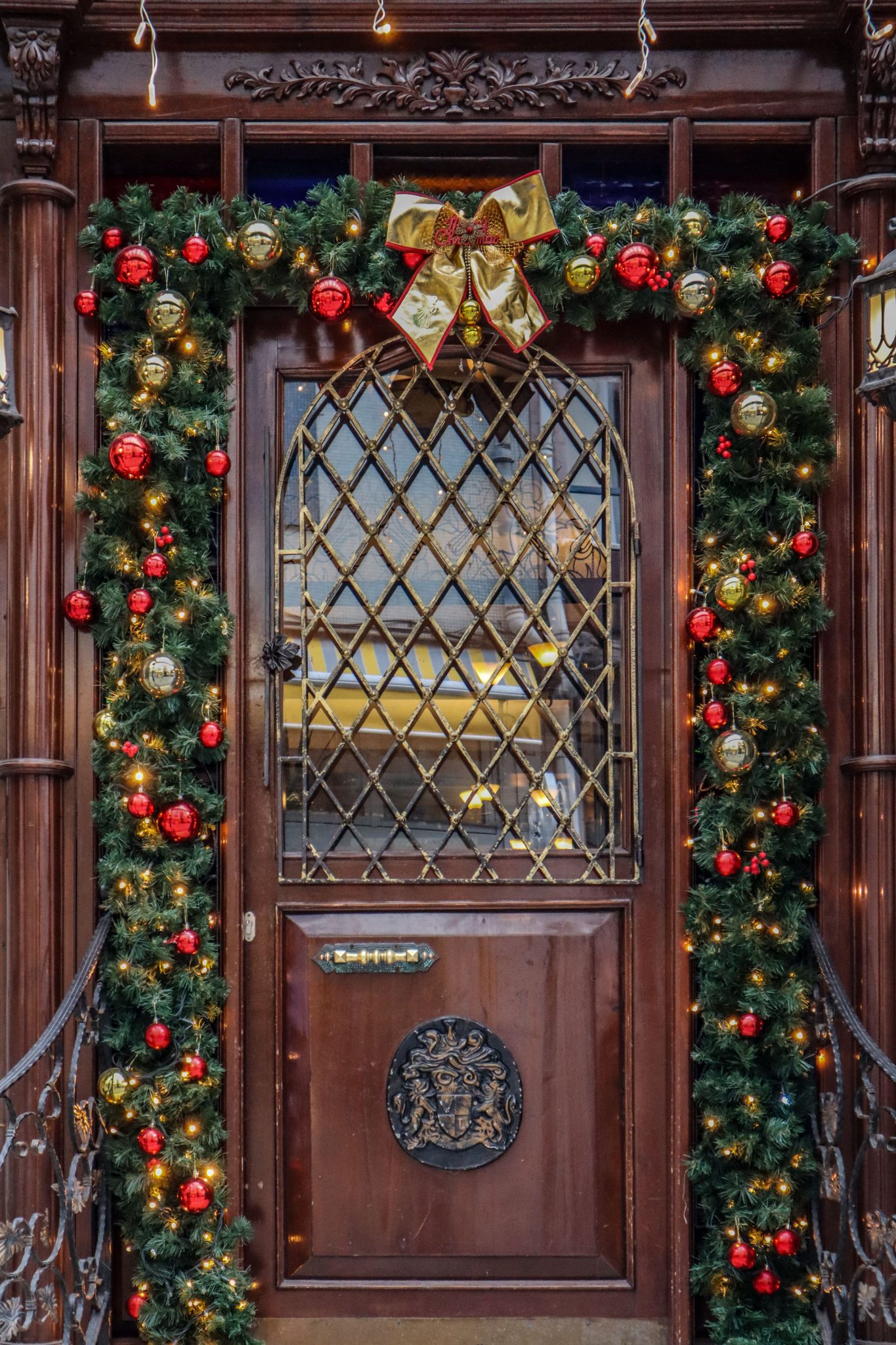 Festively adorned wooden door with Christmas garland and ornaments.