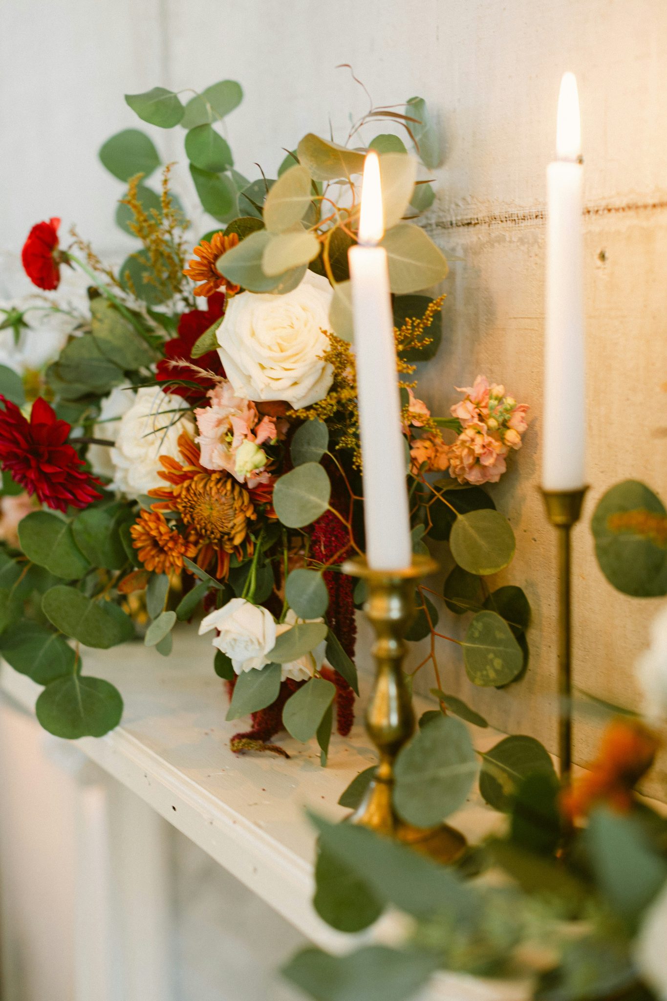 Floral arrangement with lit candles on a shelf