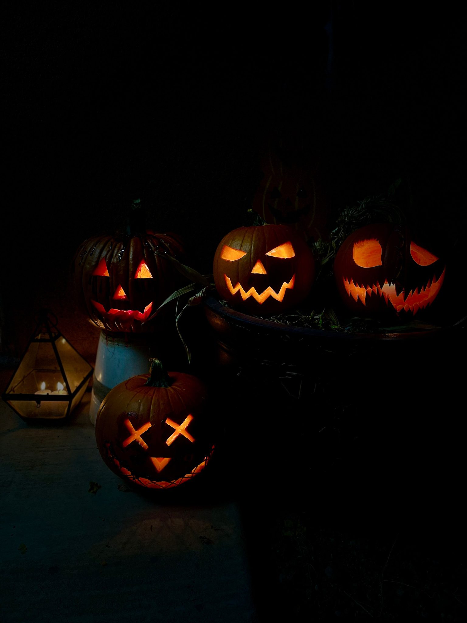 Four glowing carved pumpkins create a spooky Halloween decoration in a dark setting.