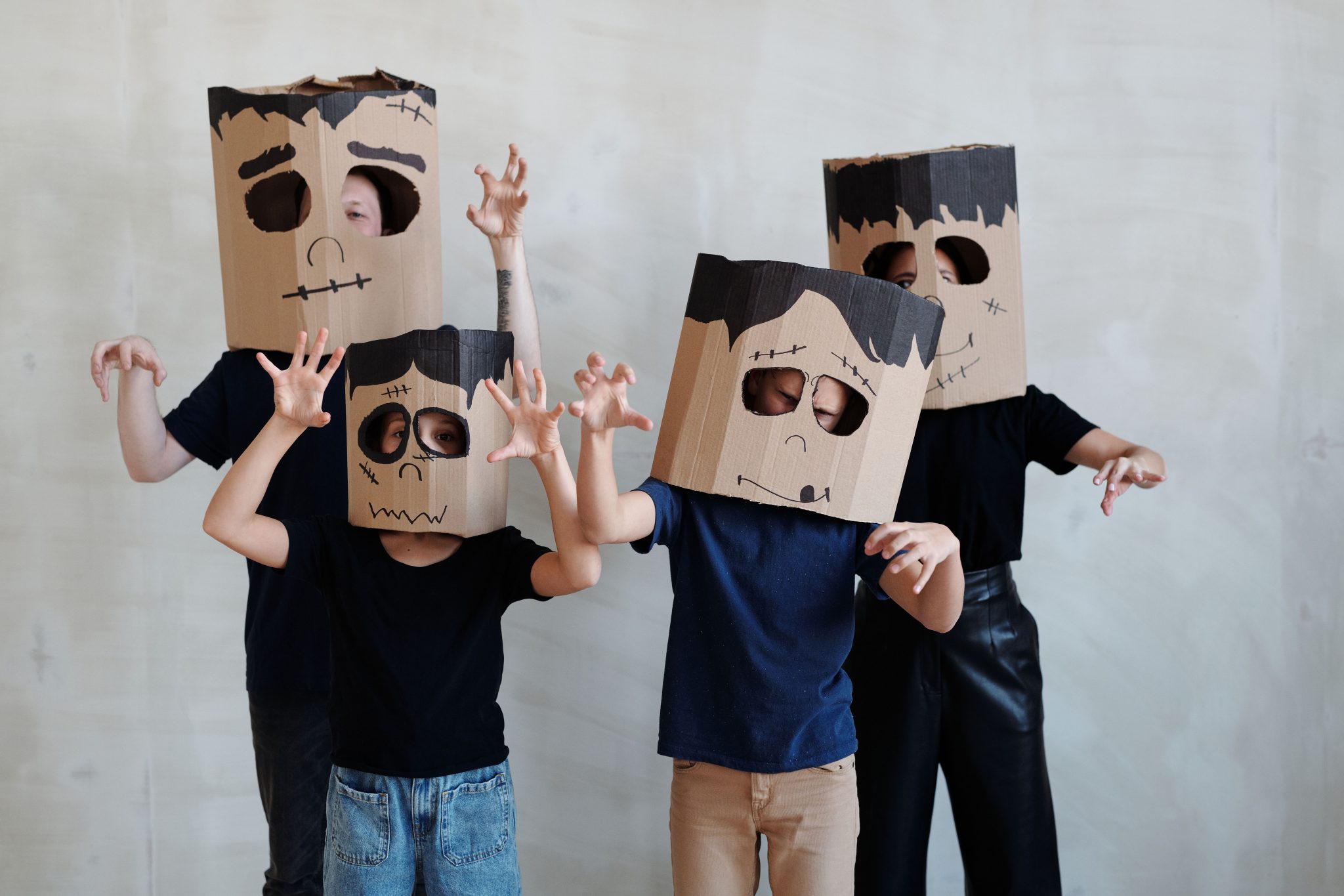 Group of children in DIY cardboard ghost costumes posing playfully for Halloween.