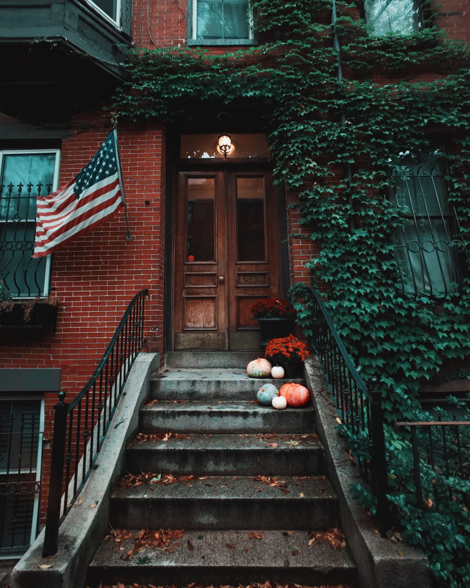 Historic Boston townhouse with American flag and pumpkins decor, perfect for fall season vibes.