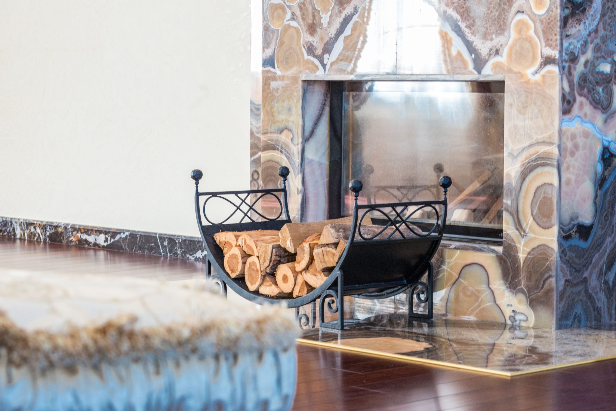 Interior of modern lounge decorated with marble fireplace with patterns and black wood rack