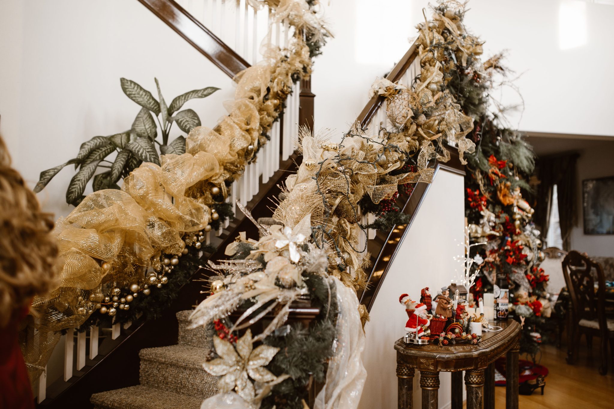 Luxurious gold and green Christmas decorations adorn an indoor staircase creating a festive atmosphere.