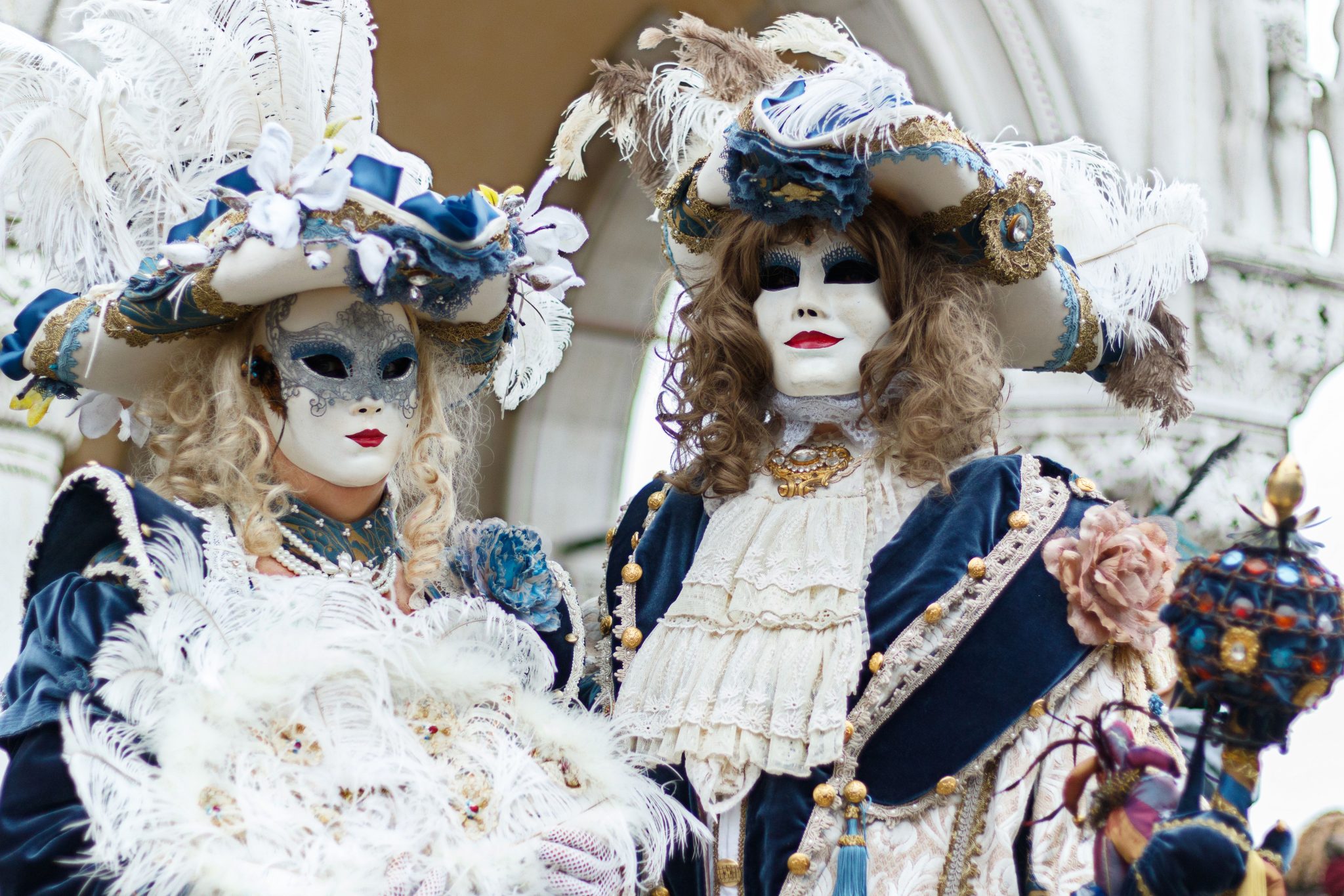 Masked individuals in ornate Venetian costumes at a carnival celebration.