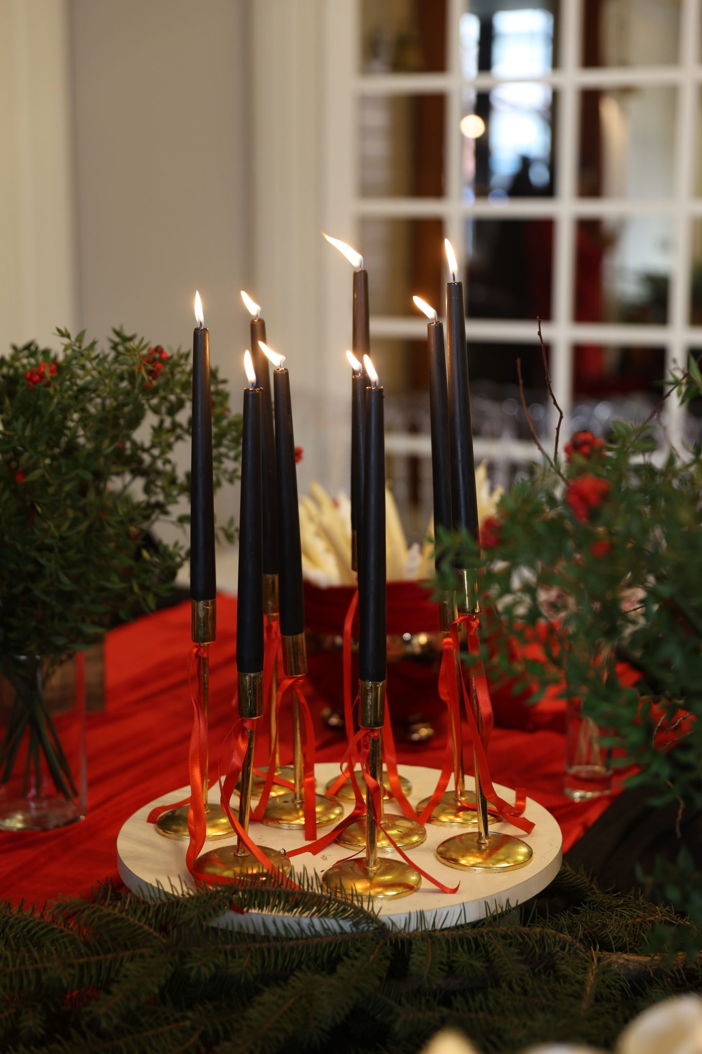 Nine lit candles with red ribbons, perfect for festive settings.