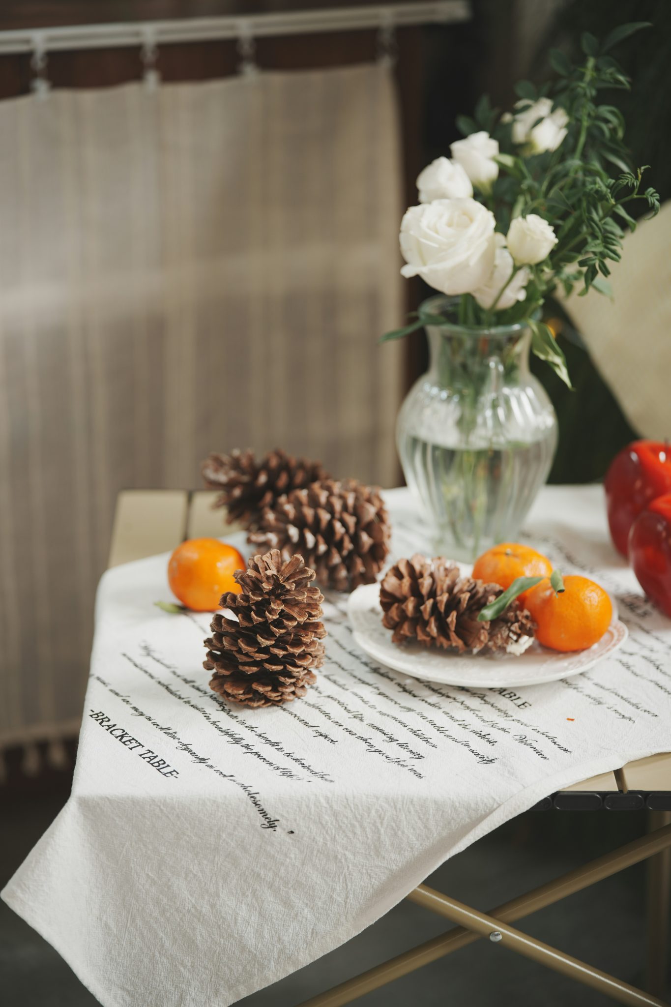 Pinecones and oranges on a table with flowers.