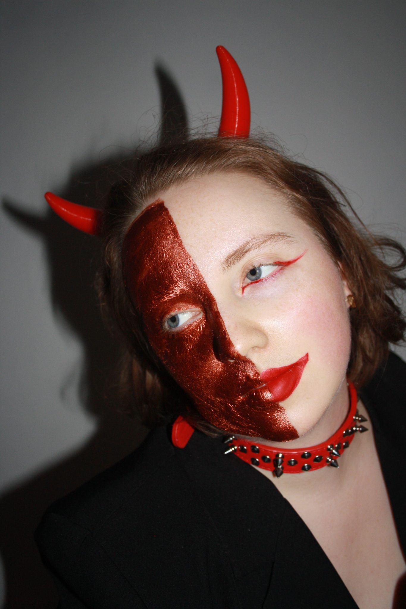 Portrait of a young woman with half devil makeup for Halloween.