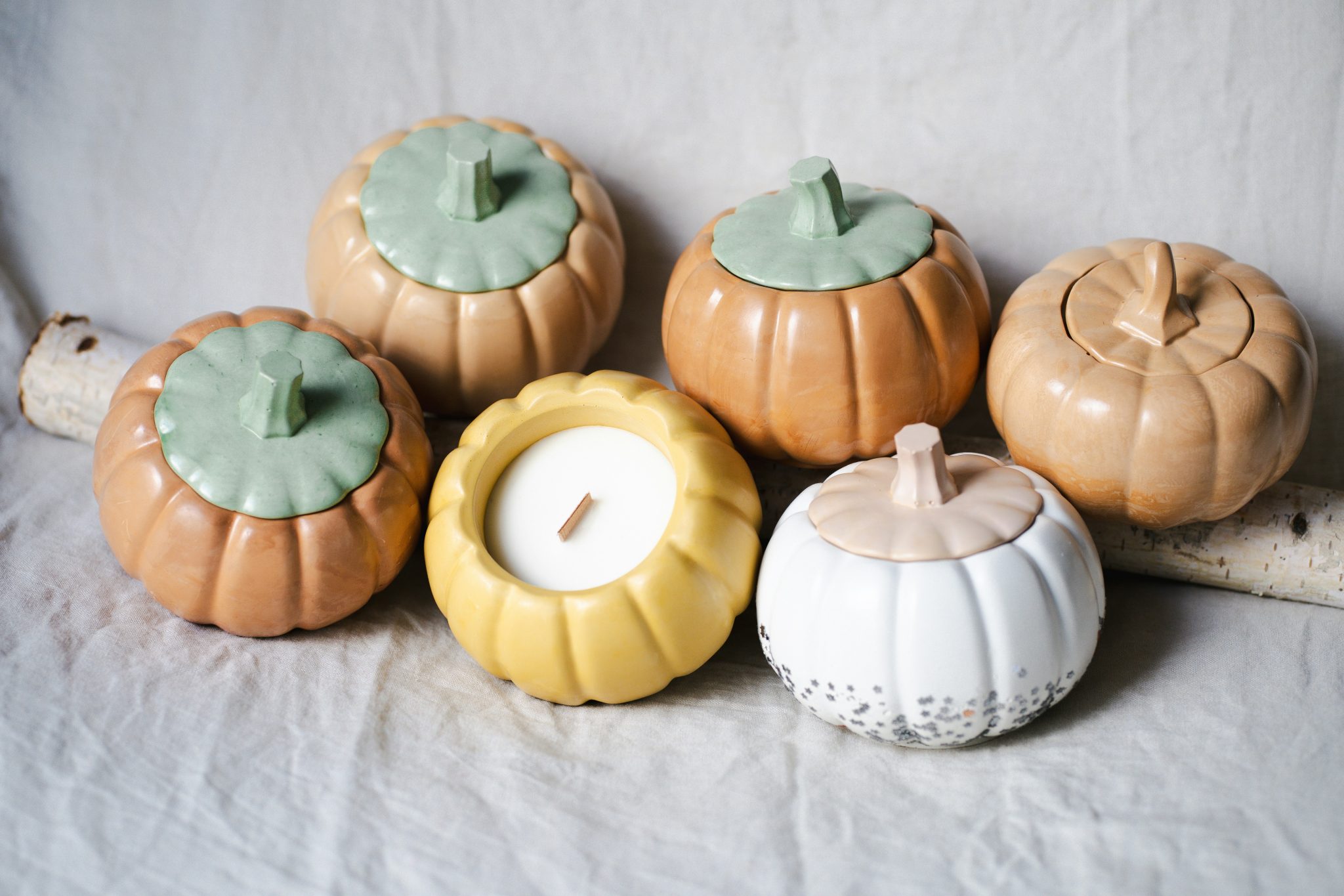Pumpkin-shaped candle holders are displayed on a white surface