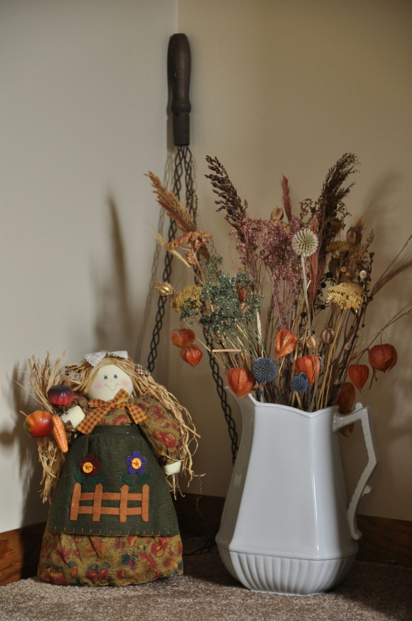 Rag doll and dried flowers in a white pitcher