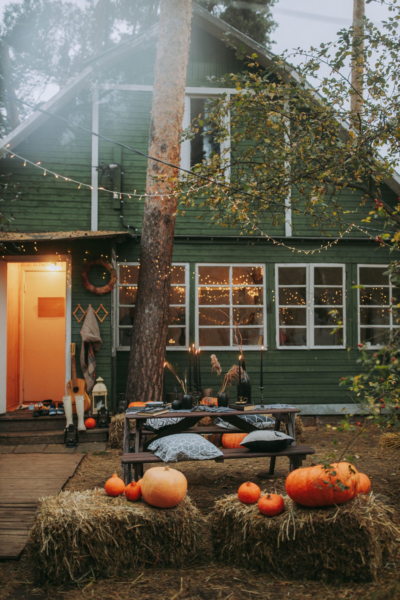 Rustic backyard with pumpkins, hay bales, and candles celebrating Halloween.