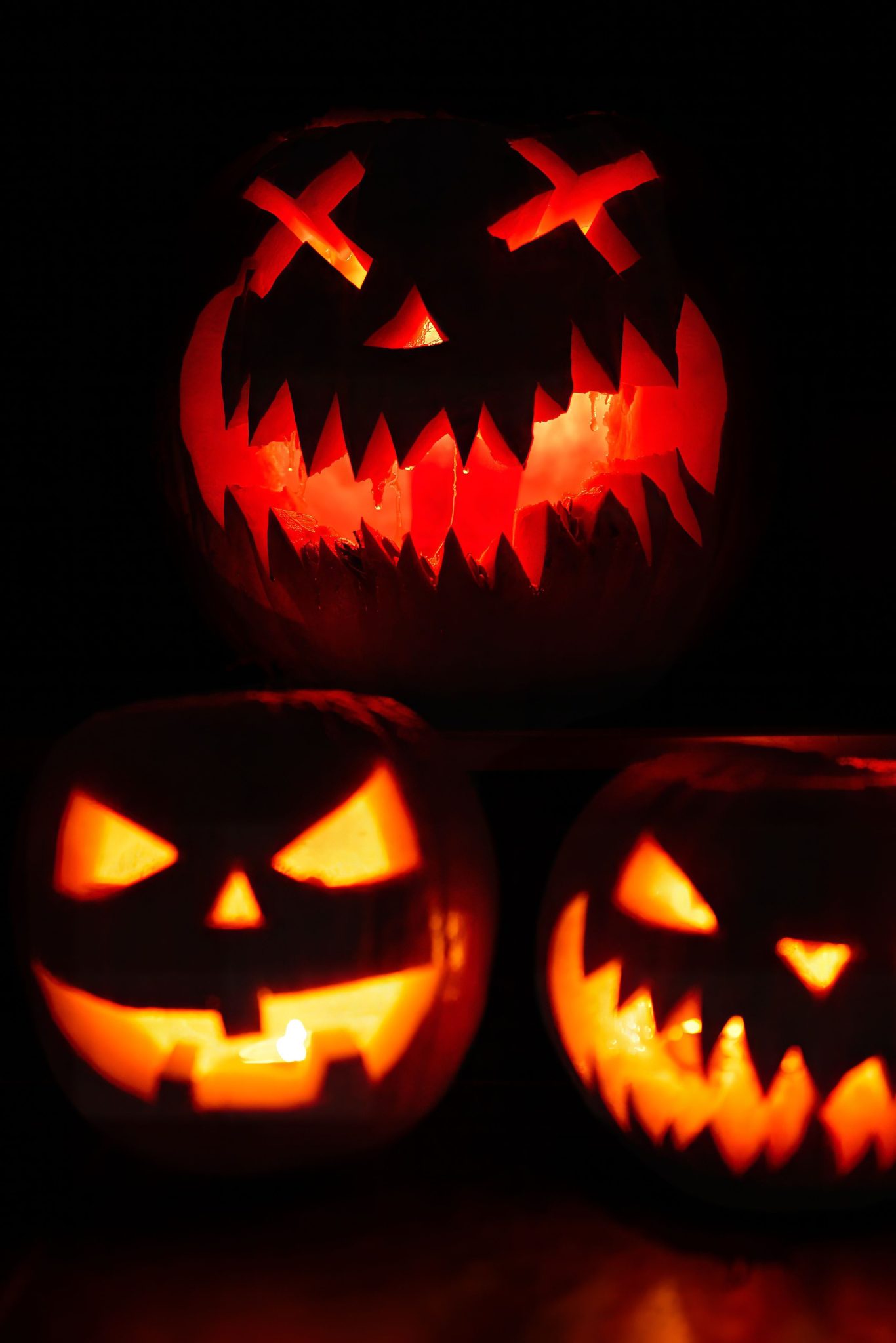 Three illuminated jack-o'-lanterns creating a spooky Halloween atmosphere.