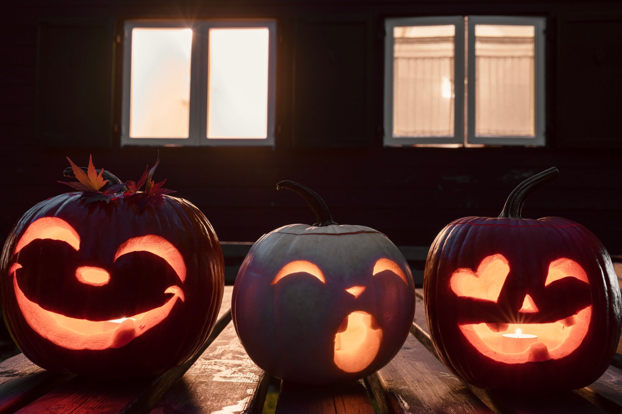 Three illuminated jack-o'-lanterns with carved faces, perfect for Halloween ambiance.